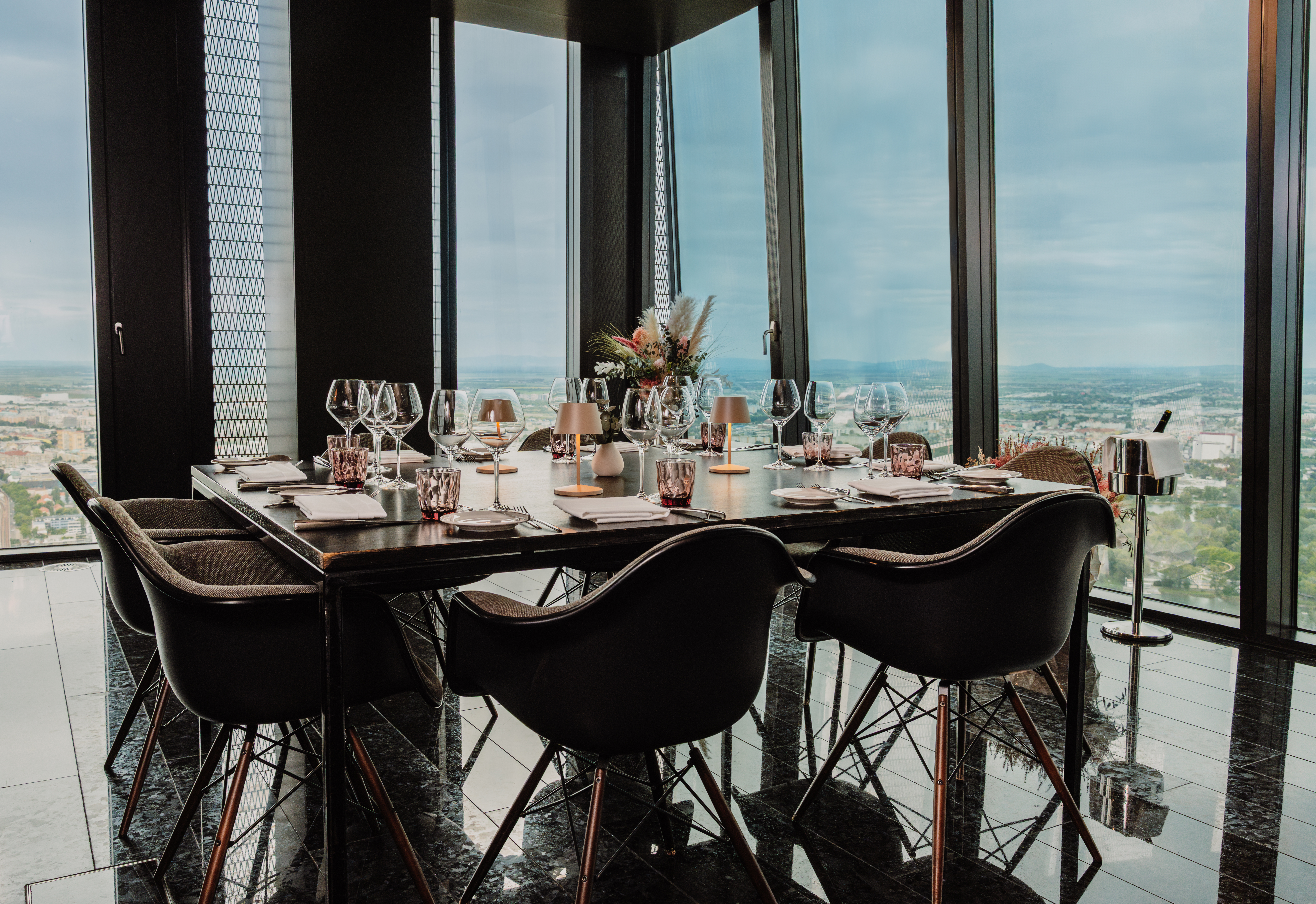 a table with wine glasses and a vase of flowers in front of a window