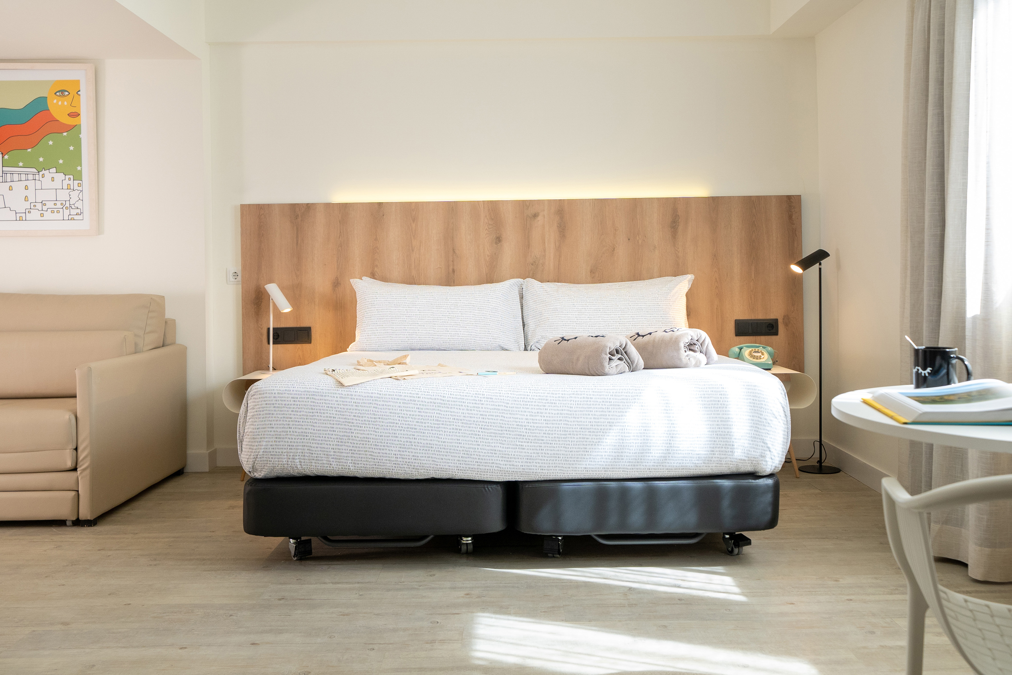 Bright modern hotel room with bed, sofa, and natural light.