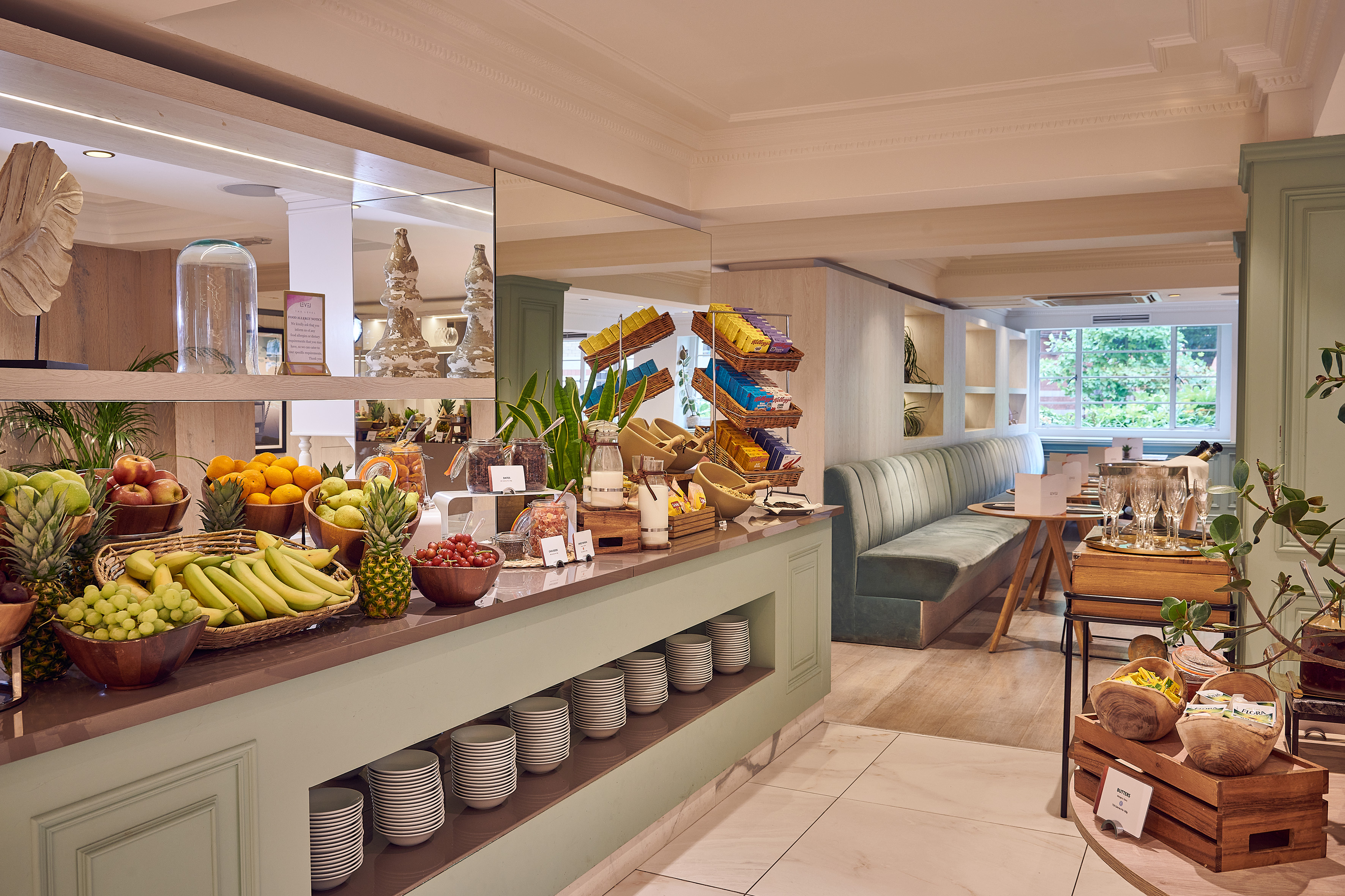 Hotel breakfast buffet with fresh fruit, cereals, and modern dining area.