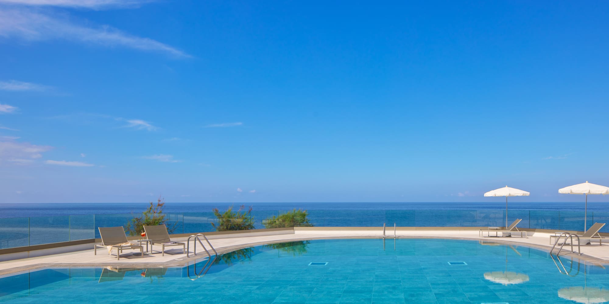 a pool with chairs and a deck and a large body of water