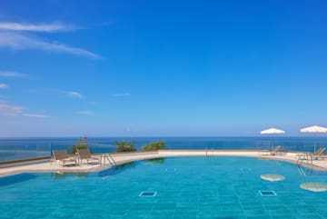 a pool with chairs and a deck and a large body of water
