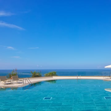 a pool with chairs and a deck and a large body of water