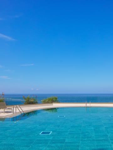 a pool with chairs and a deck and a large body of water