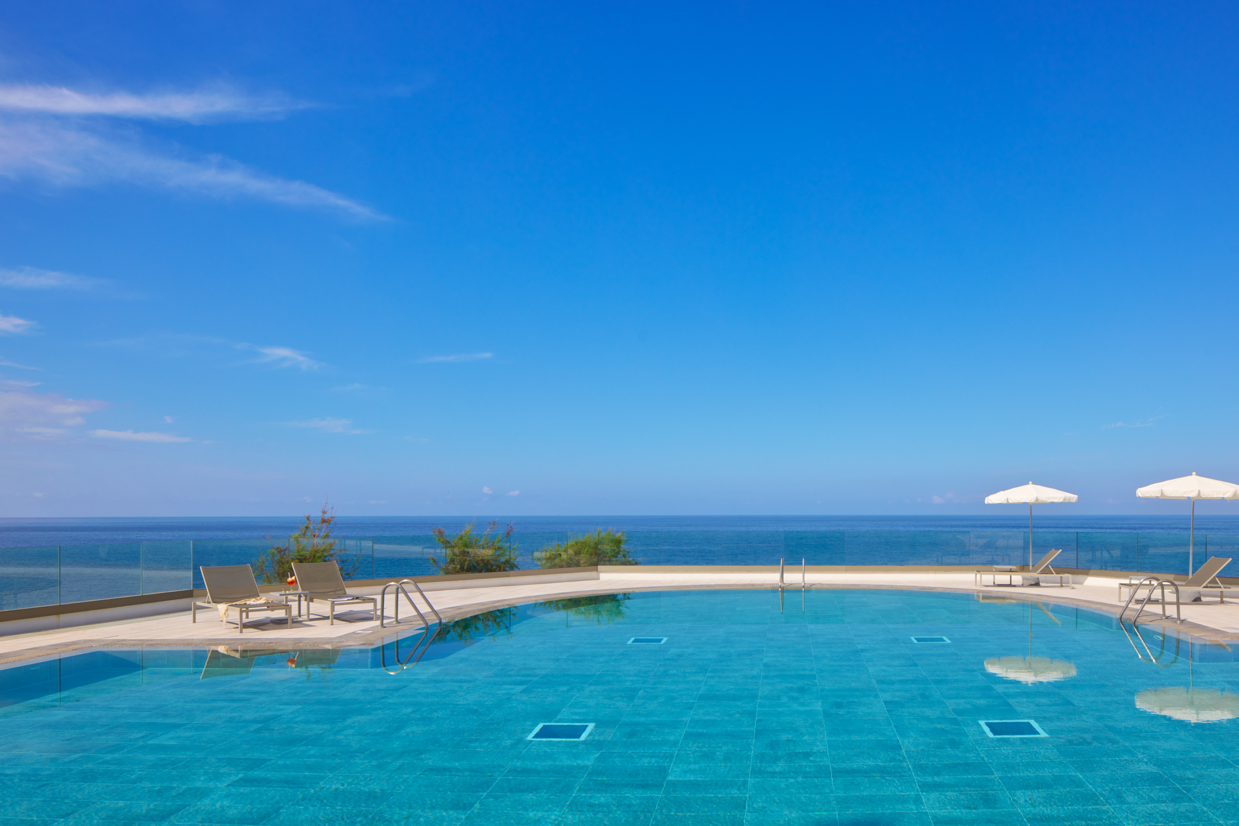 a pool with chairs and a deck and a large body of water