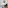 Modern hotel room with green armchair, wooden table, lamp, and abstract art.