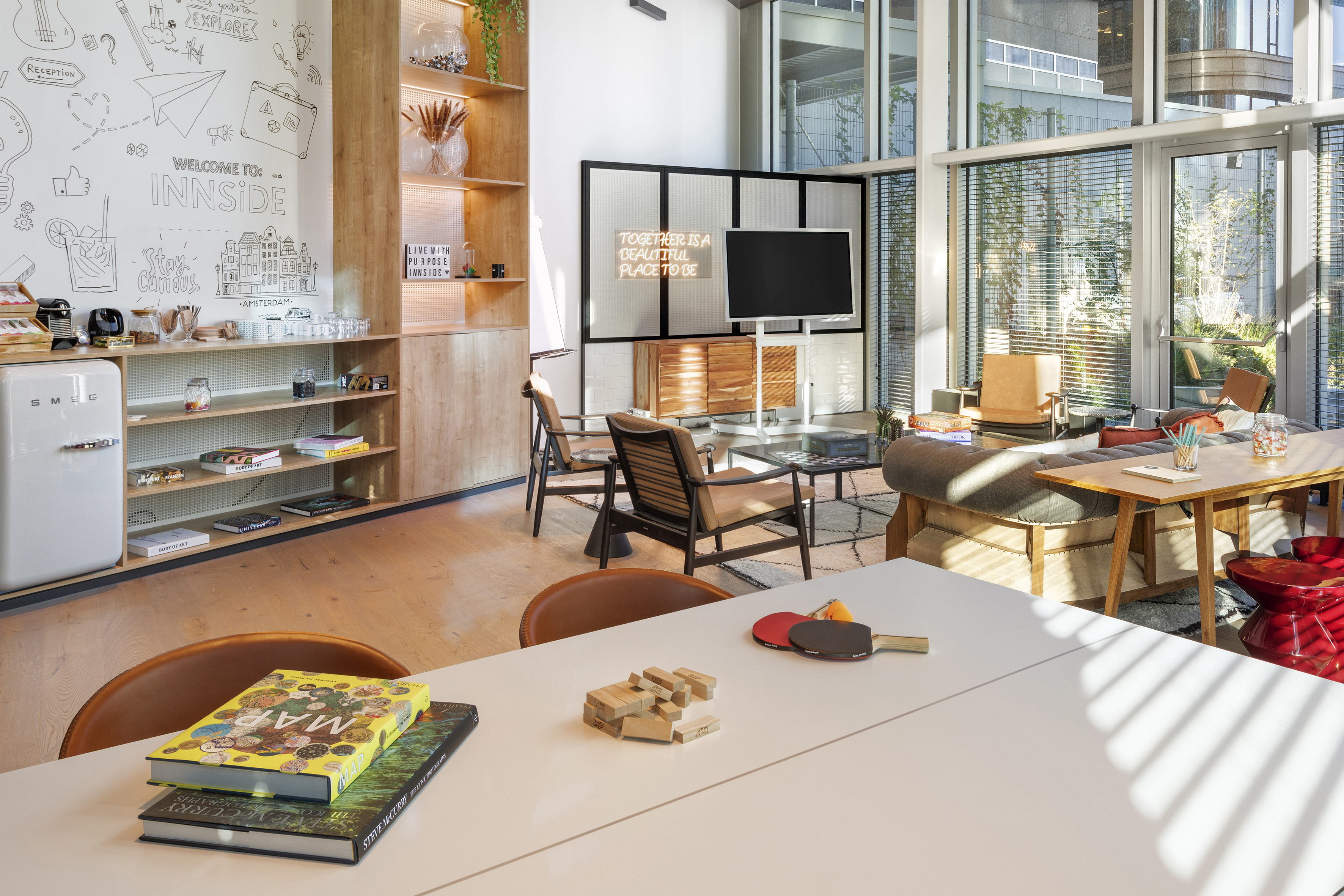 Contemporary INNSIDE hotel lounge with stylish seating, SMEG fridge, and games.