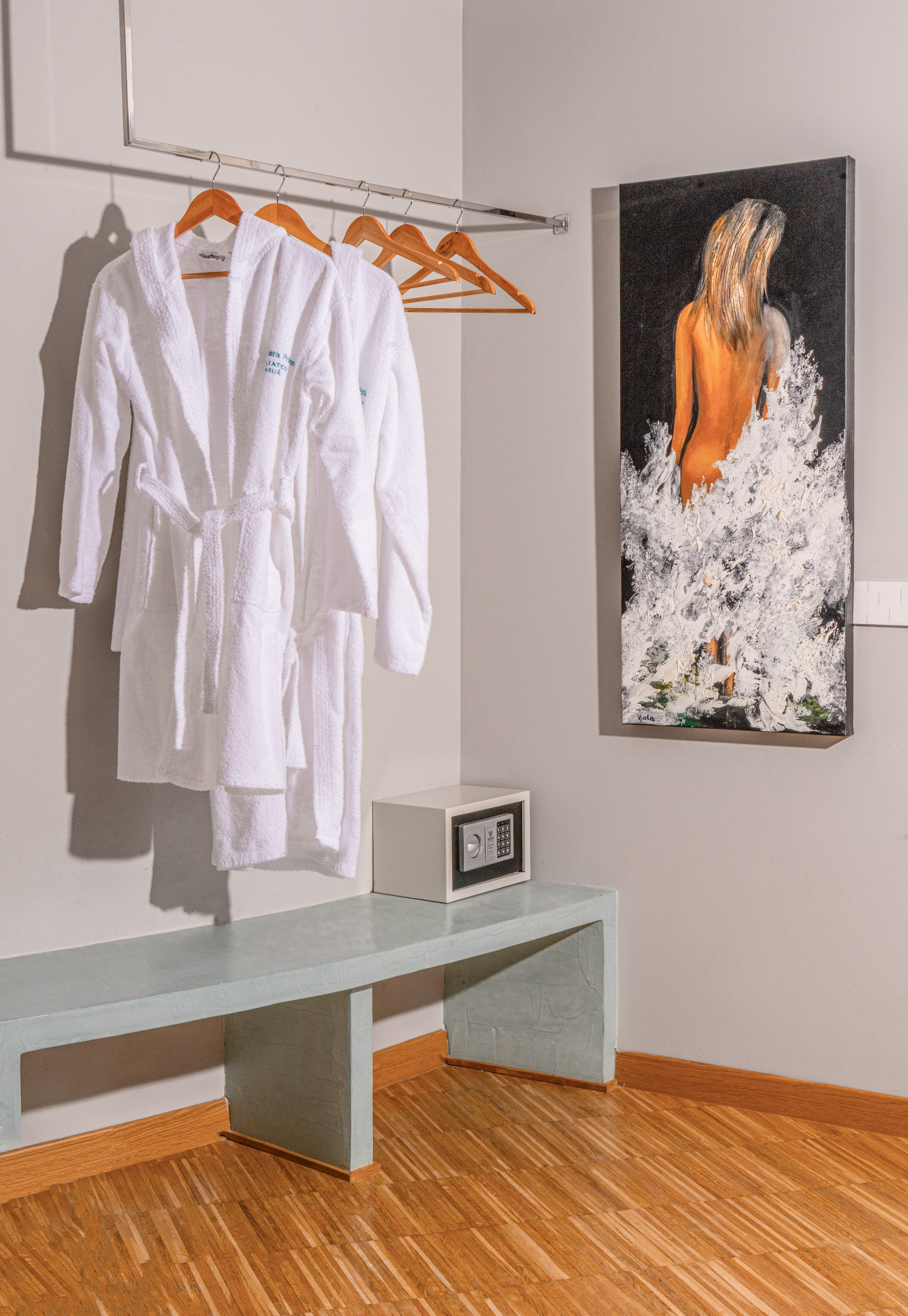 White hotel bathrobes, security safe, and modern art in a guest room.