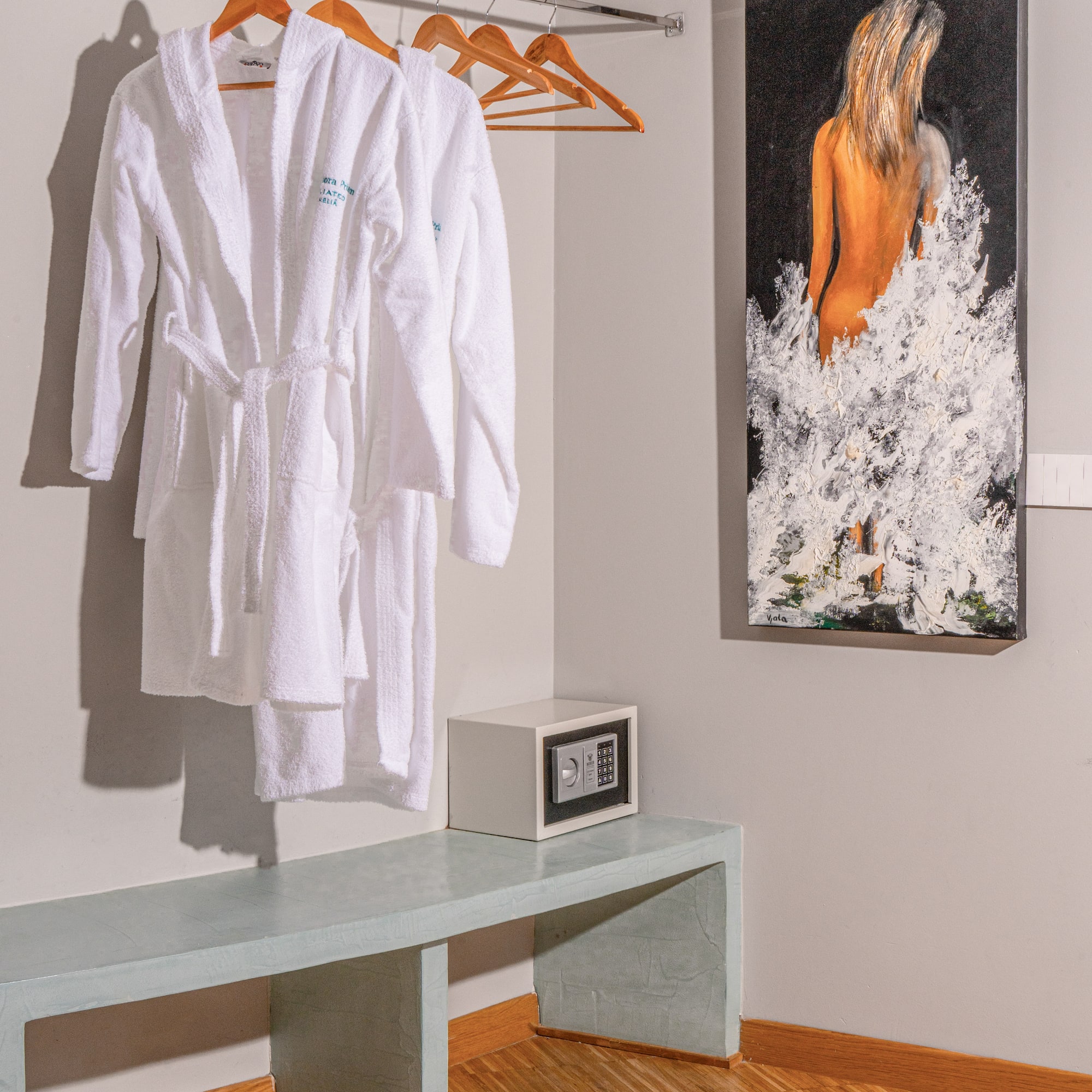 White hotel bathrobes, security safe, and modern art in a guest room.
