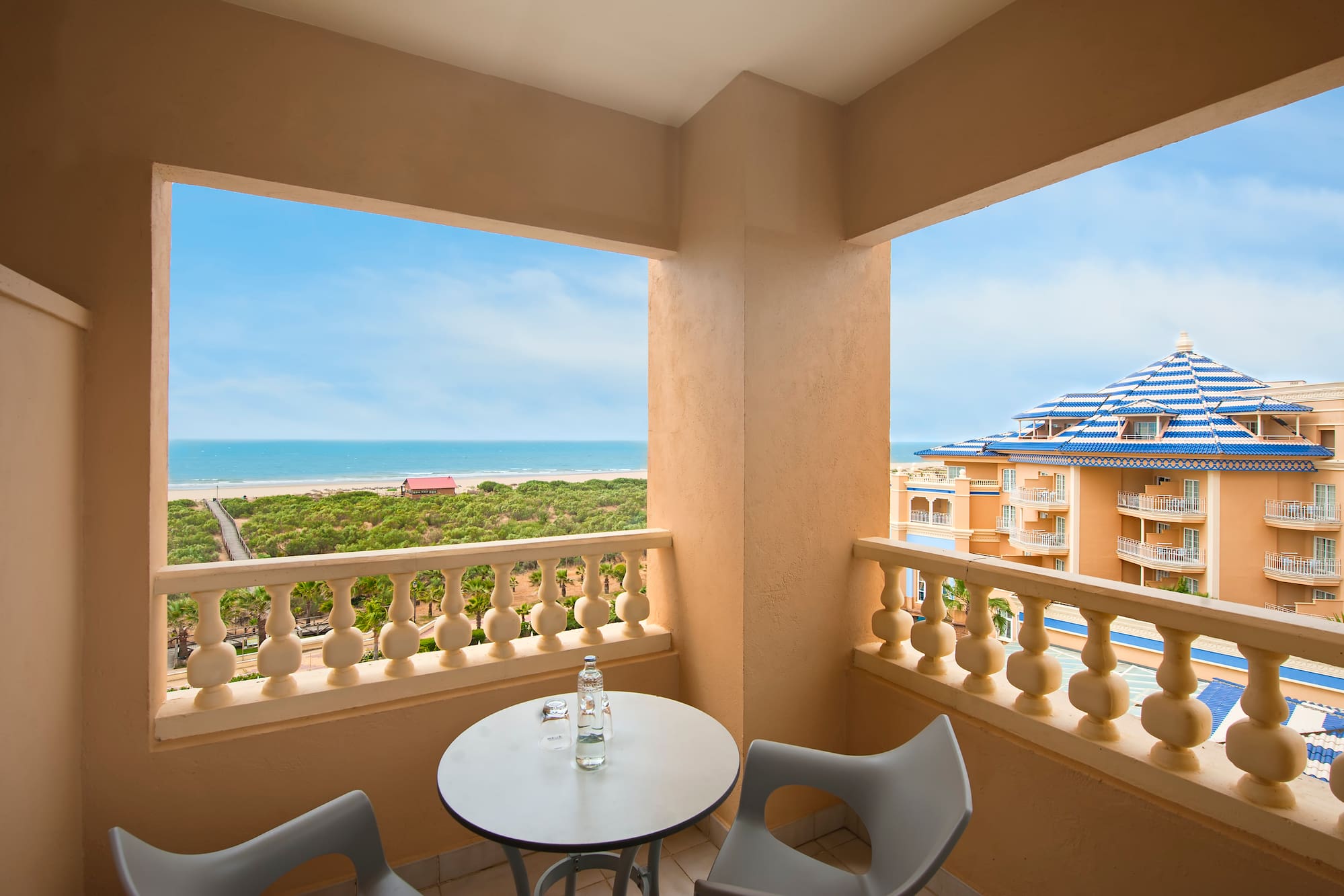 a balcony with a table and chairs overlooking a beach