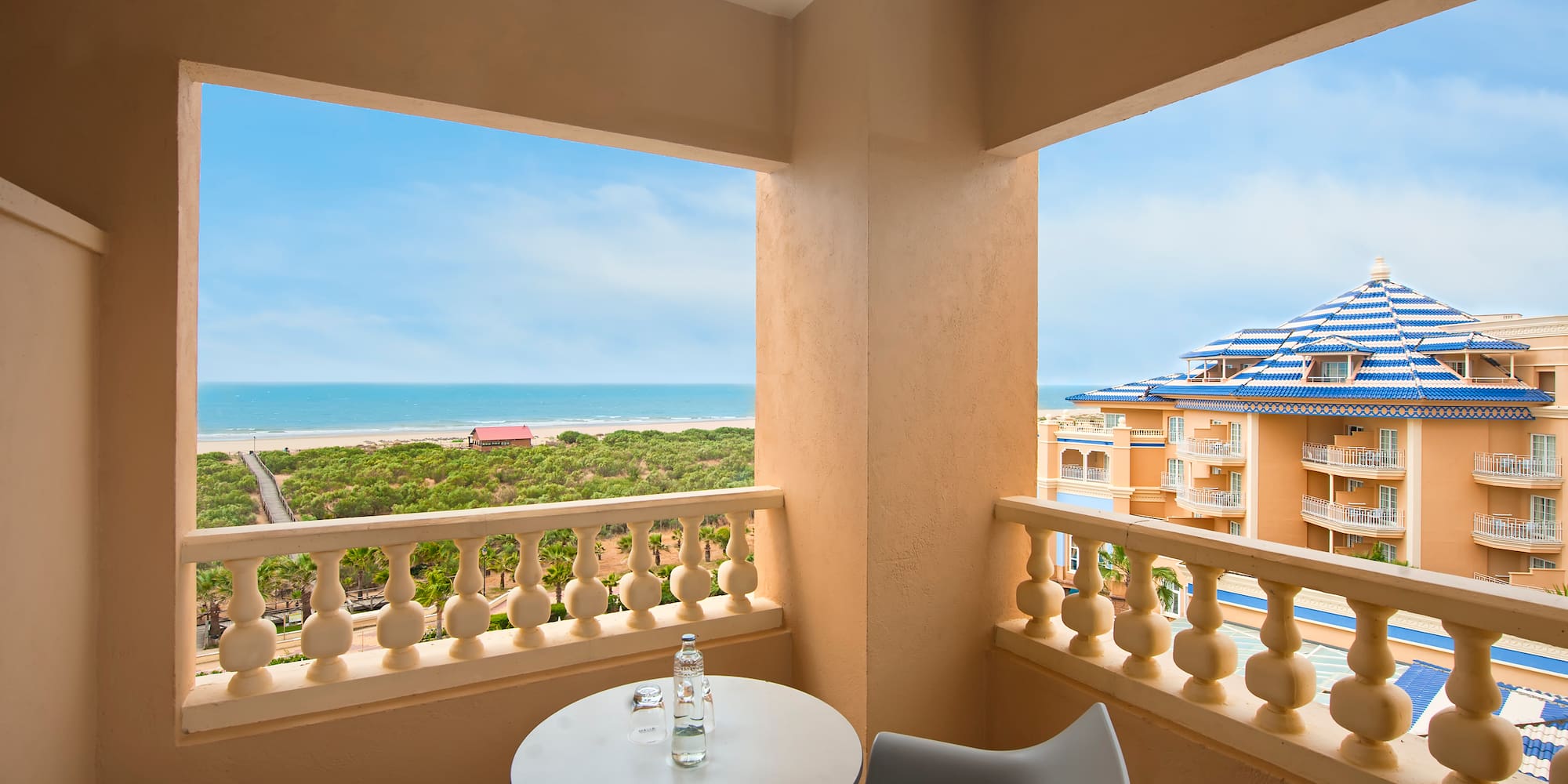 a balcony with a table and chairs overlooking a beach
