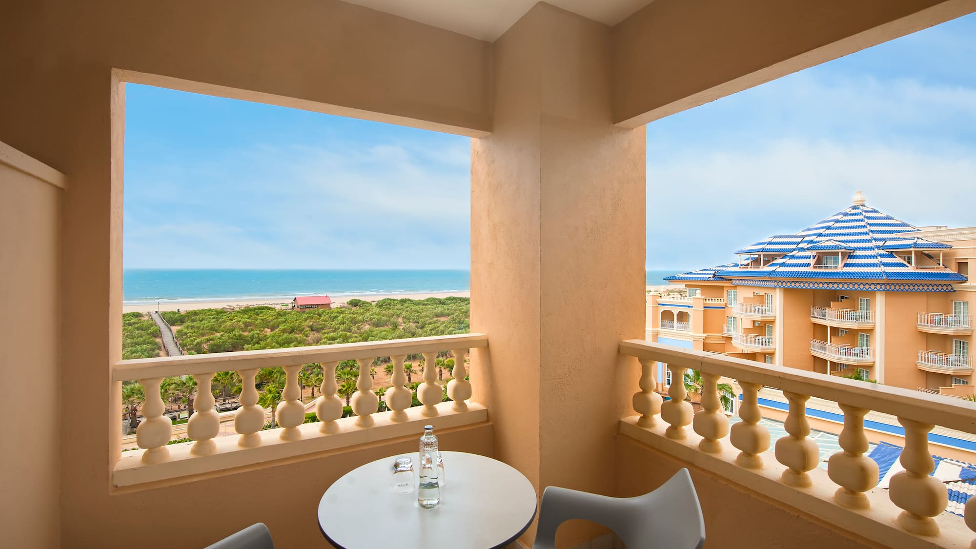 a balcony with a table and chairs overlooking a beach