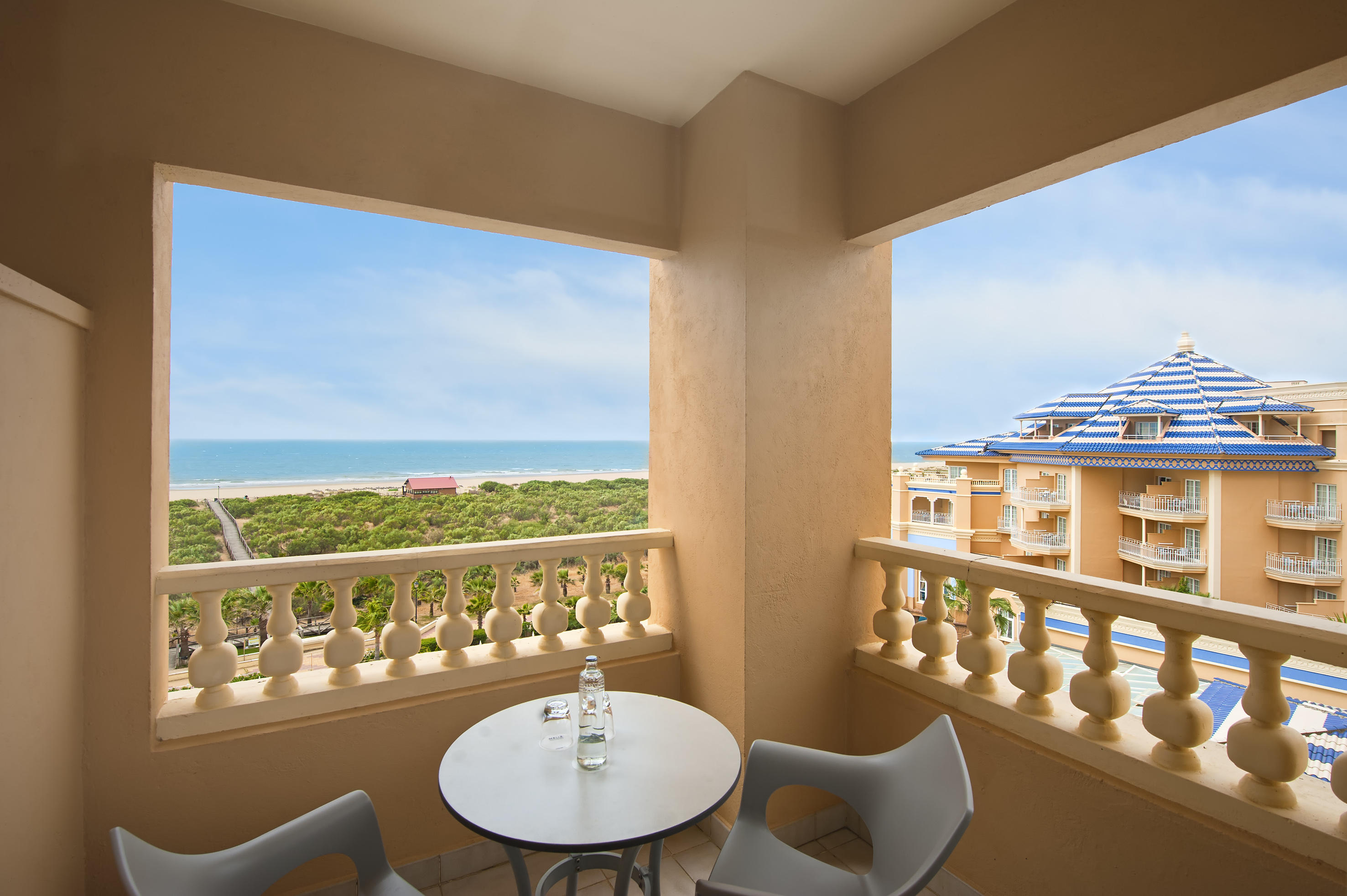 Hotel balcony with sea view, beach, and resort building.