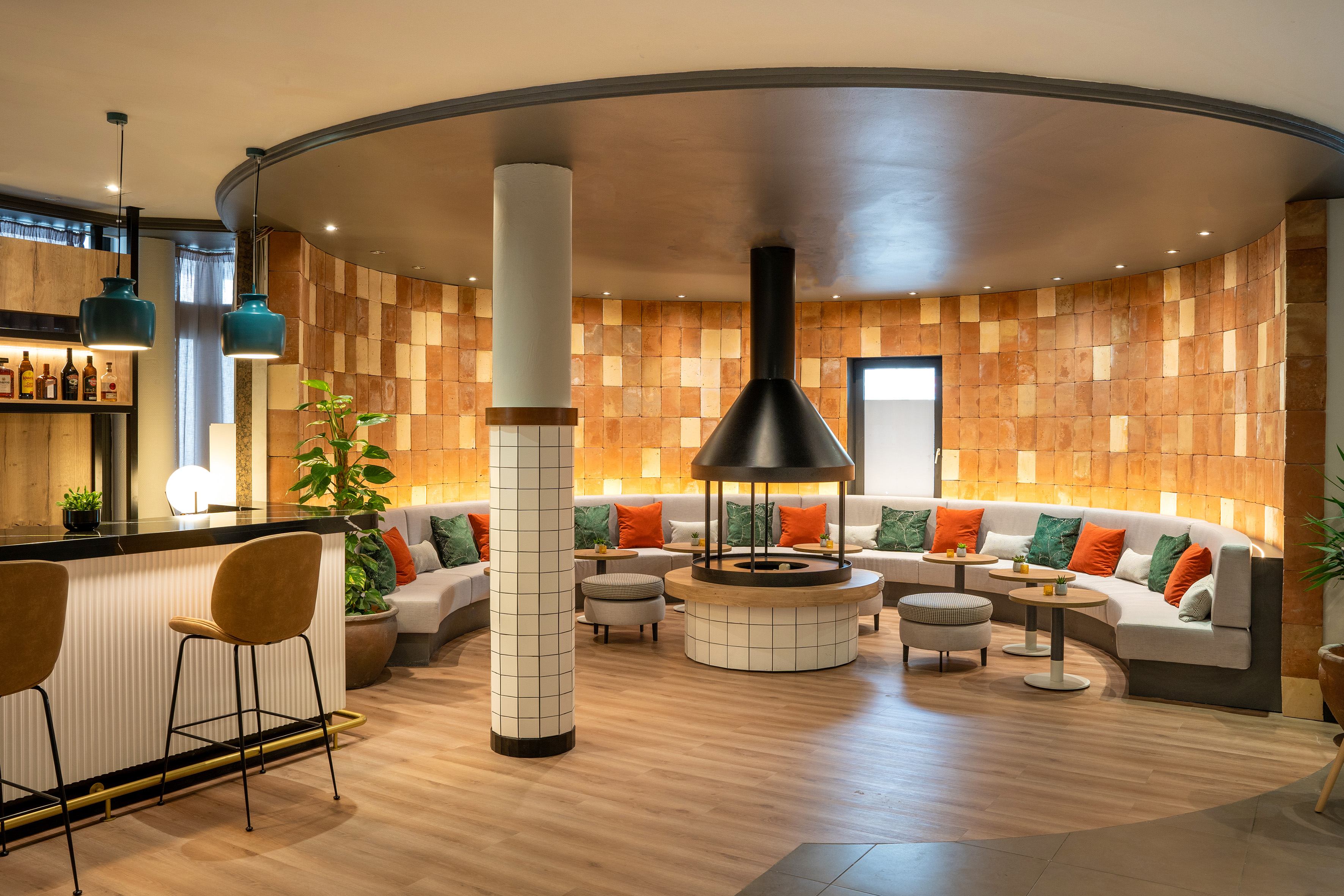 Cozy modern hotel lounge with fireplace, curved seating, and bar.