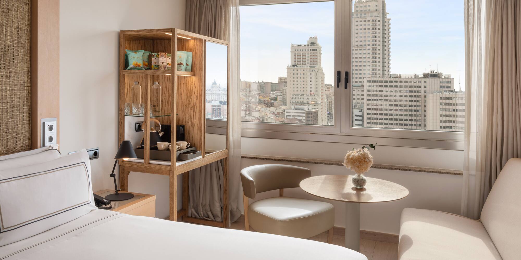 Bright modern hotel room with panoramic Madrid city skyline view.