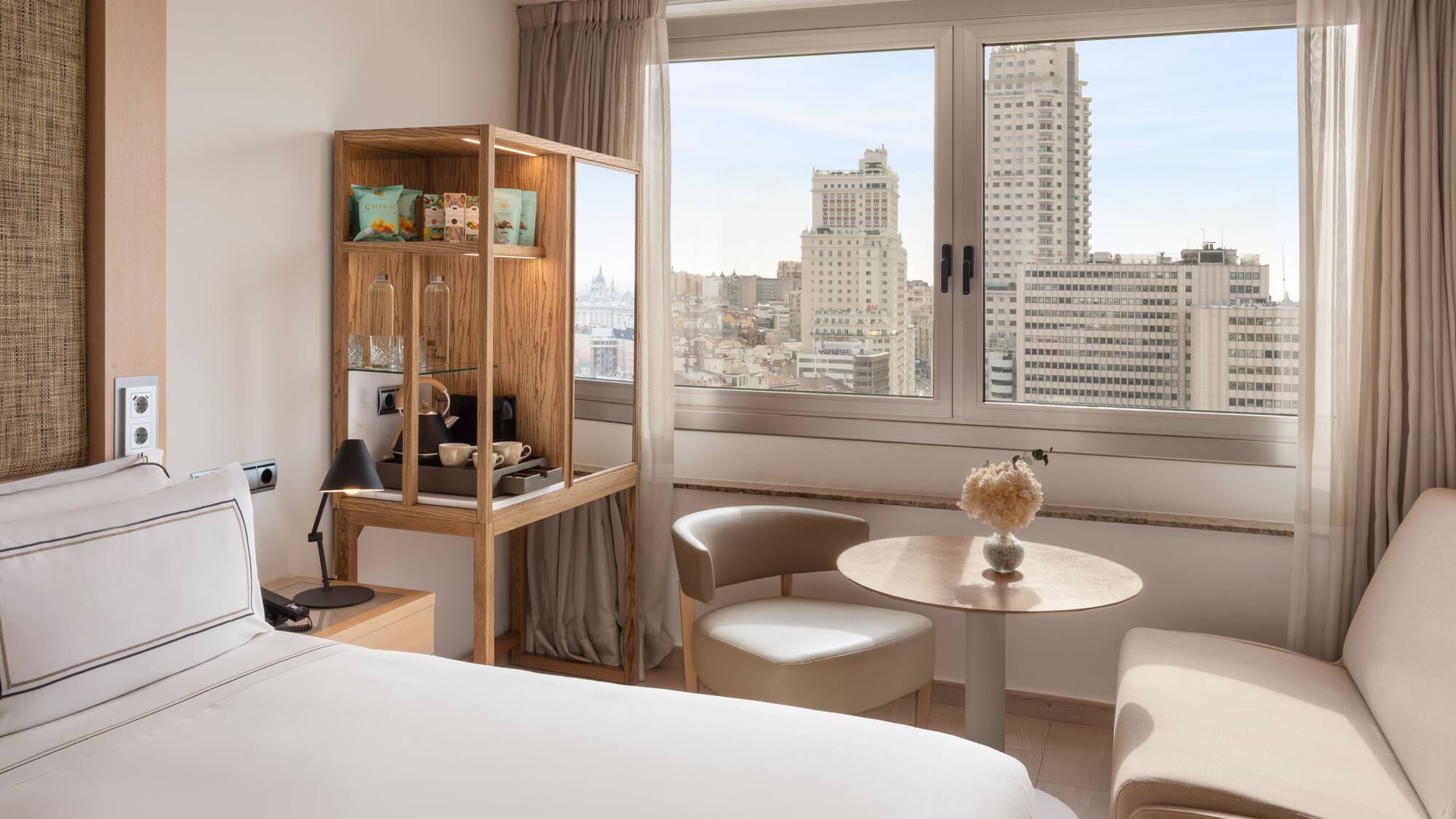 Bright modern hotel room with panoramic Madrid city skyline view.