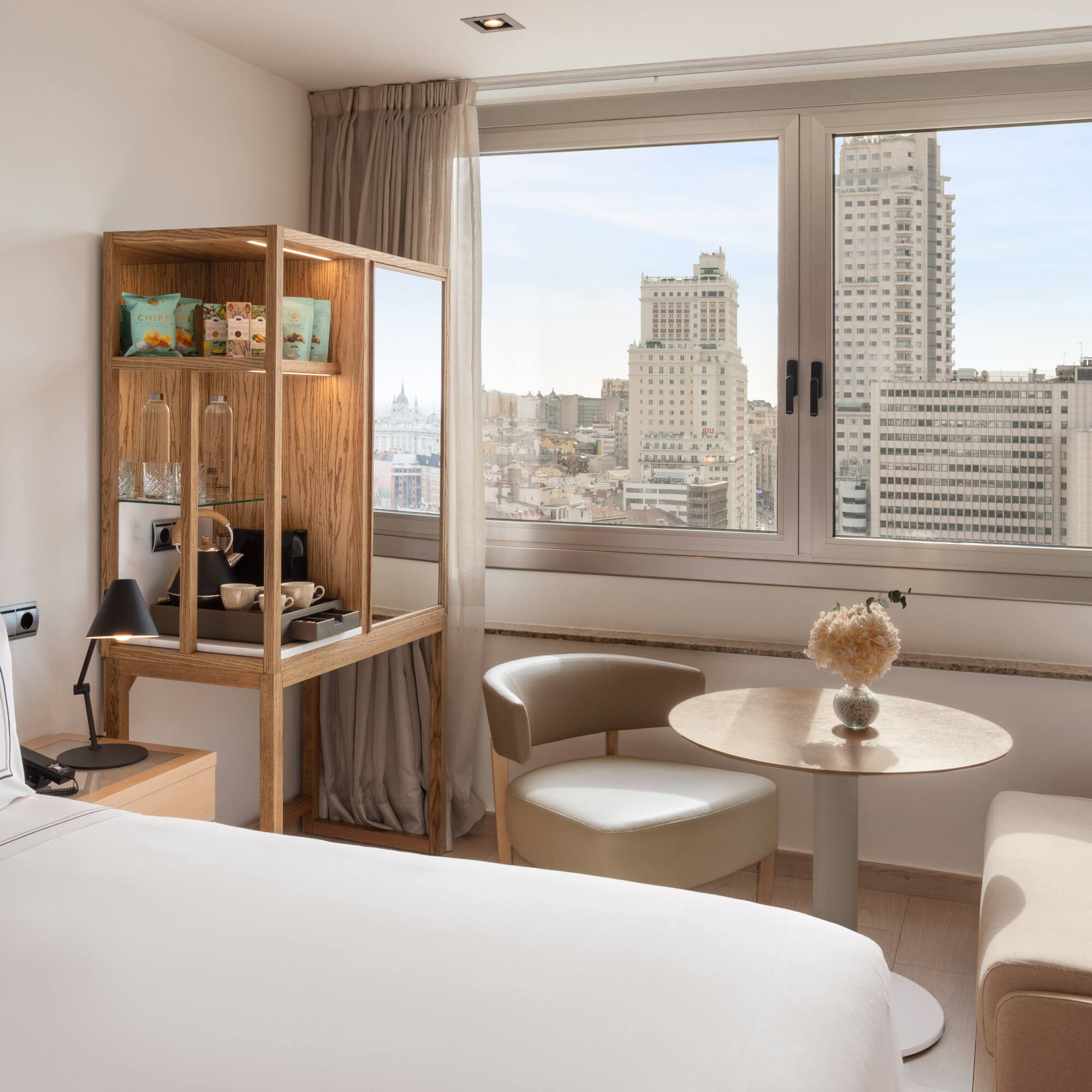 Bright modern hotel room with panoramic Madrid city skyline view.
