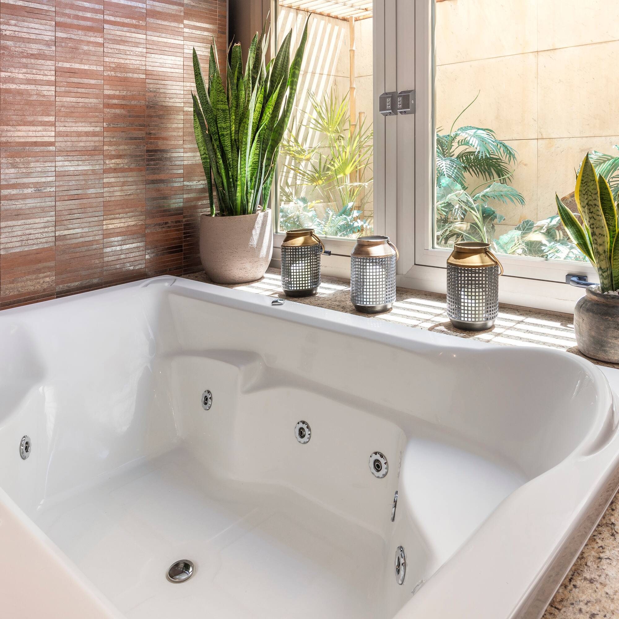 a white bathtub with a window and plants in the background