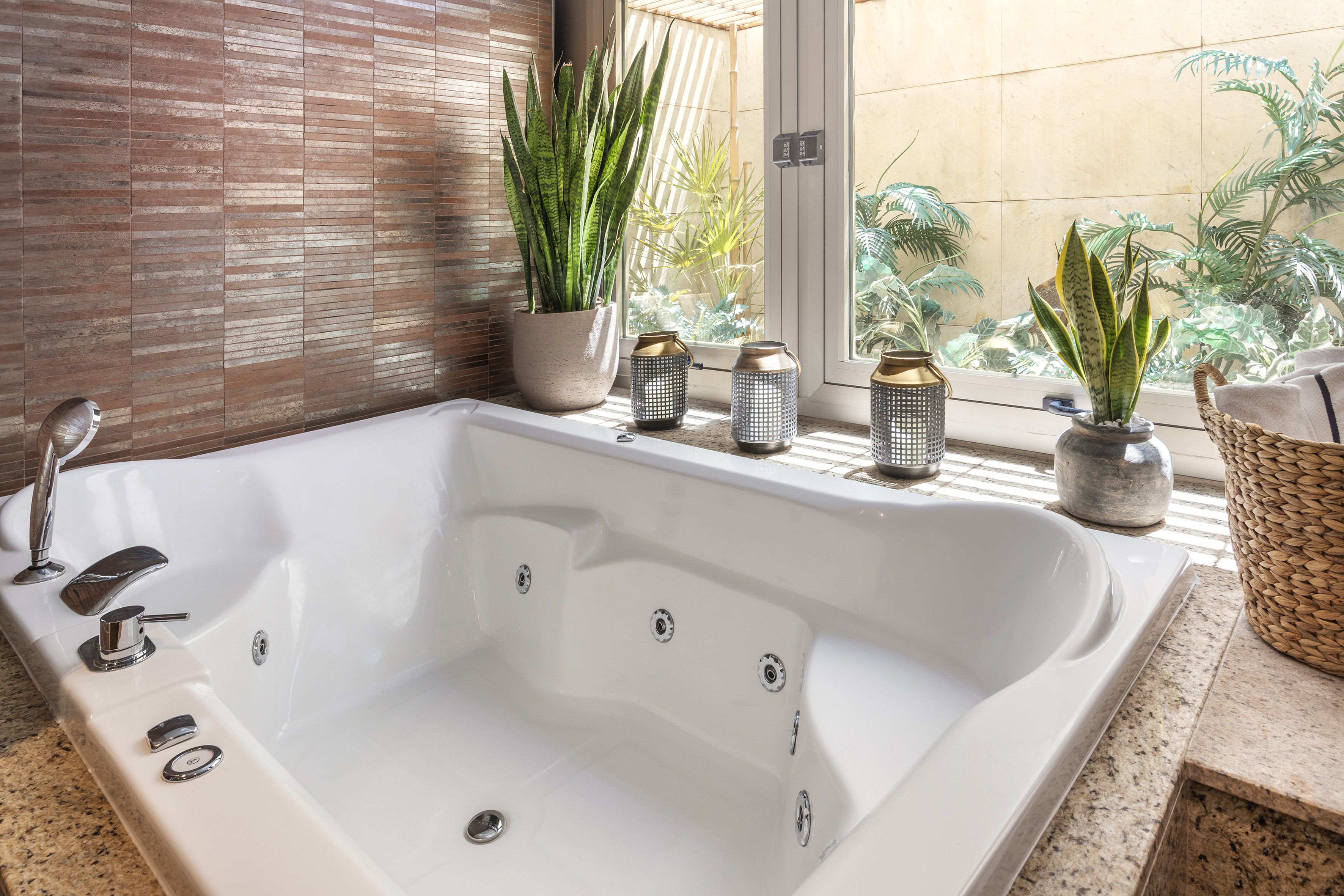 Bright bathroom jacuzzi tub with plants, modern tiles, and natural light.