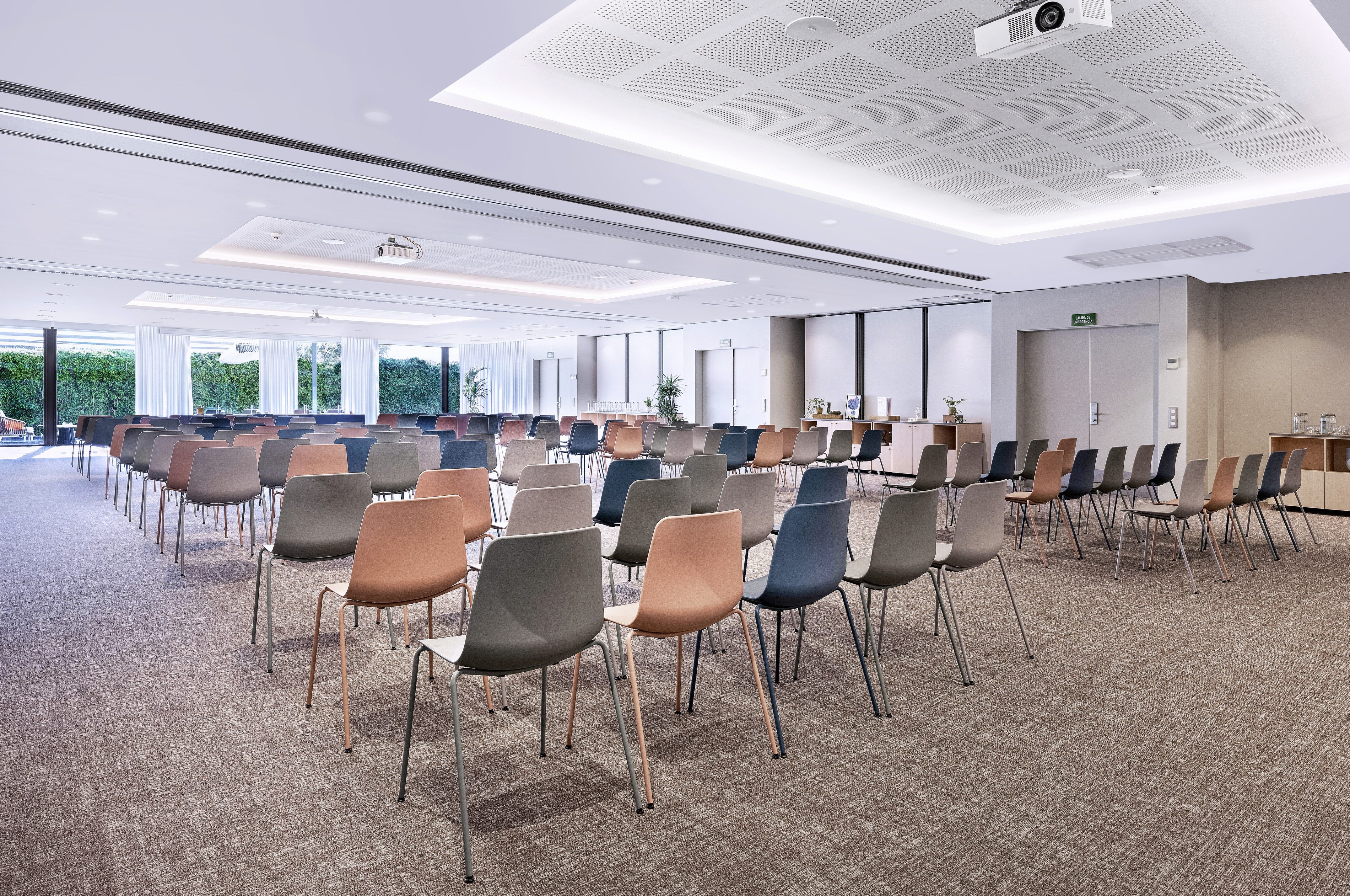 Spacious meeting room with colorful chairs, projector, and large windows.
