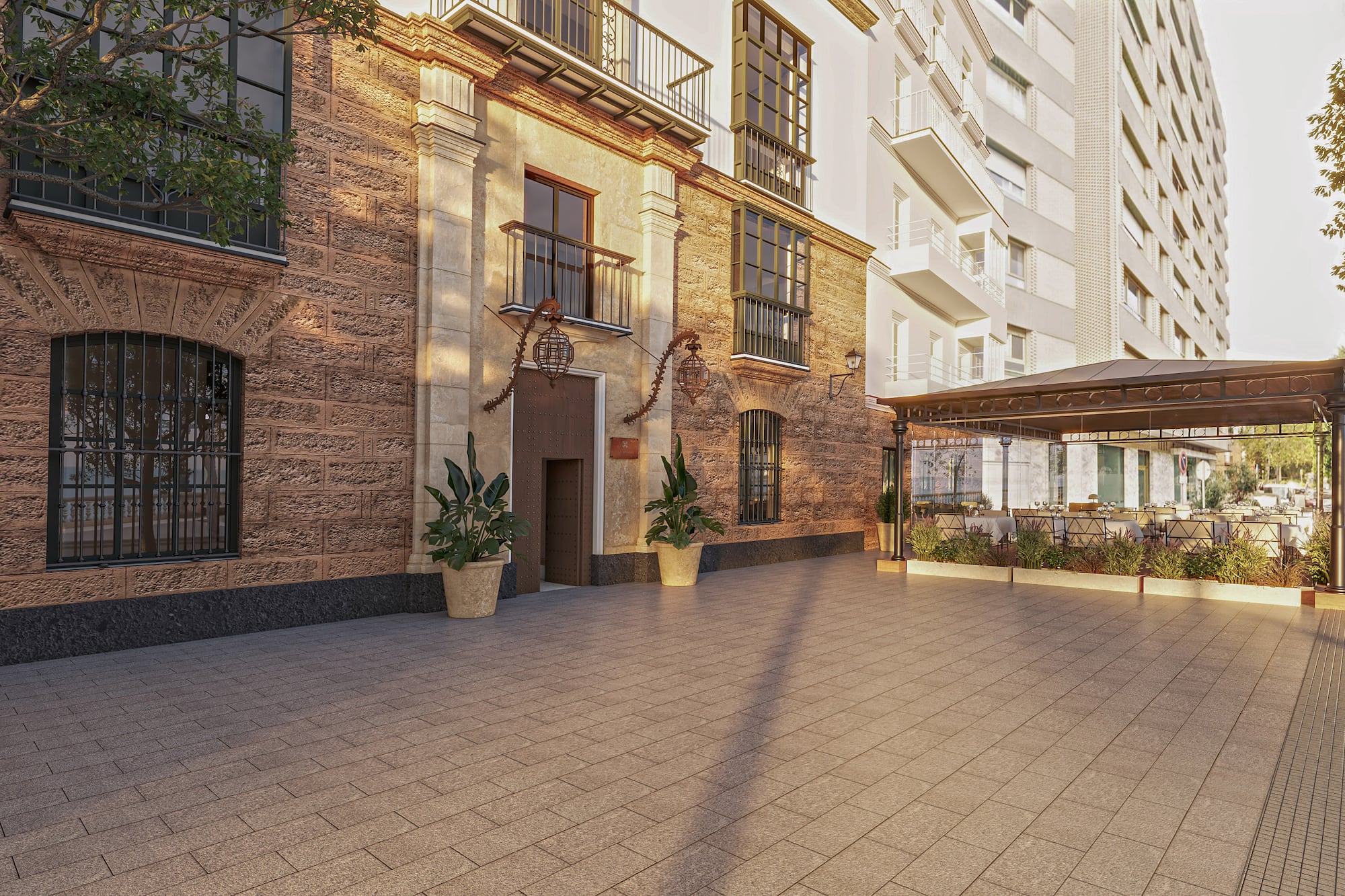 Old stone facade, modern building, paved patio, outdoor cafe terrace with tables.