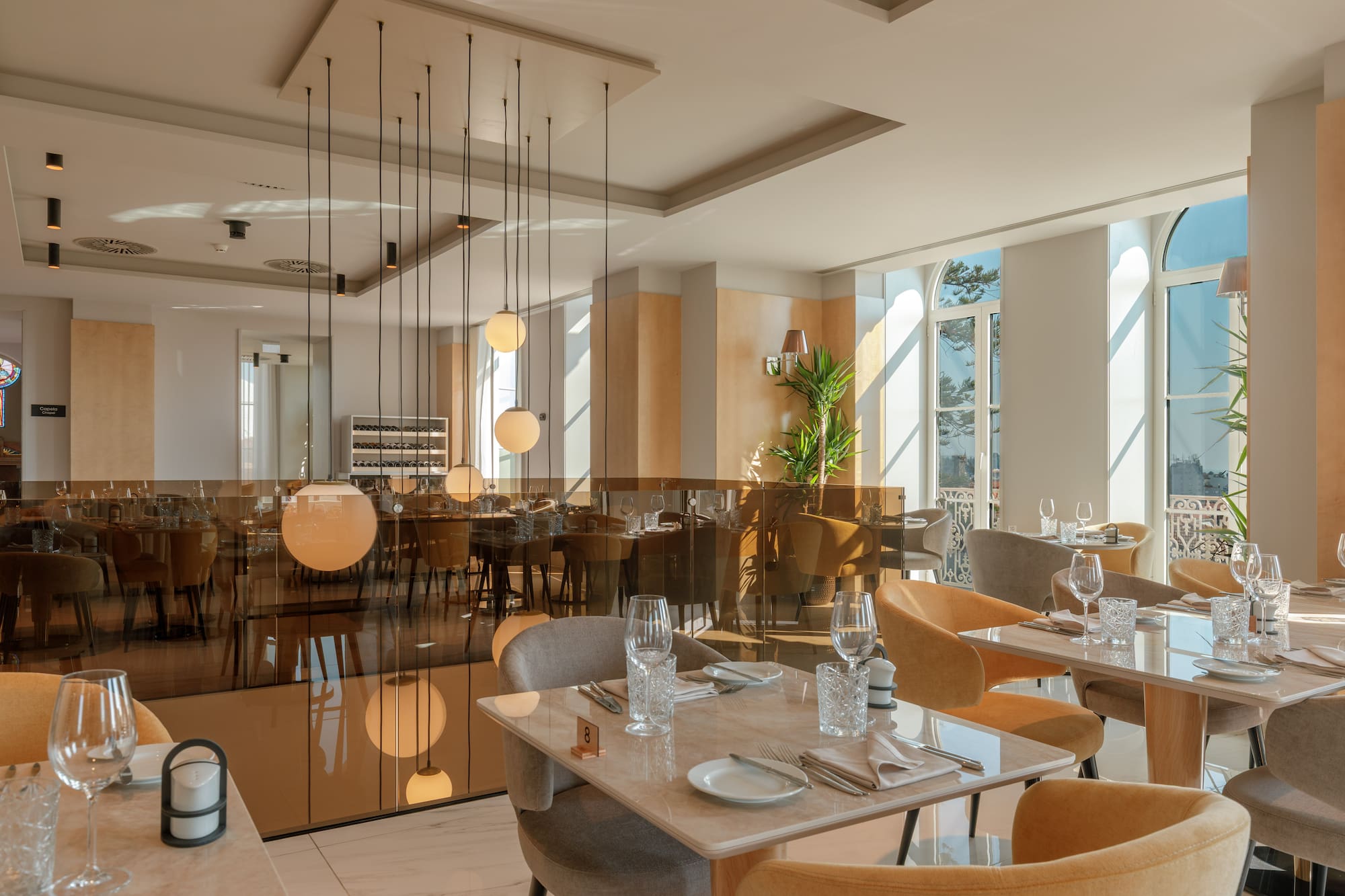 Modern restaurant dining room with set tables, natural light, and elegant decor.