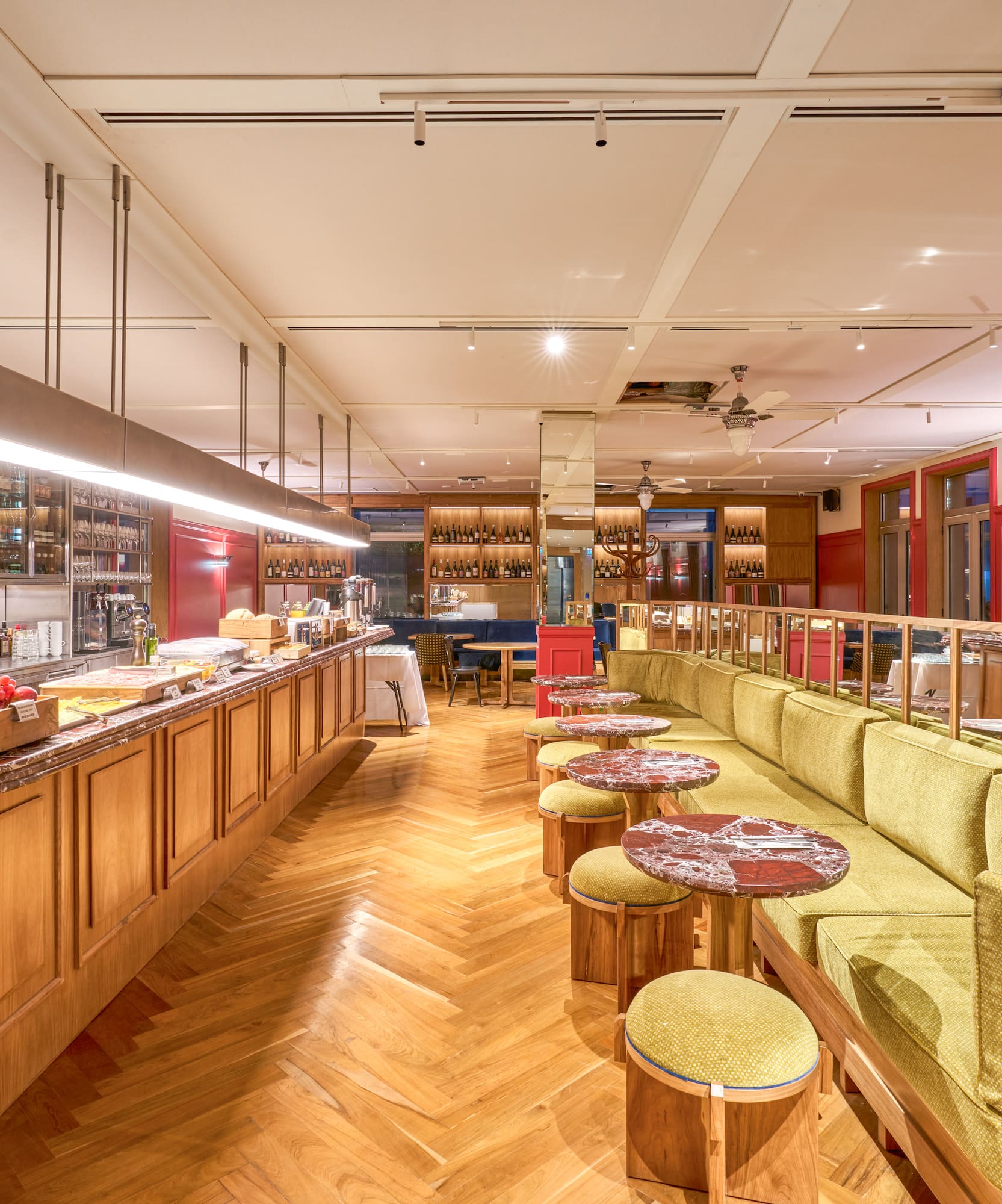 Elegant restaurant bar with green banquette, wooden floor, and modern lighting.
