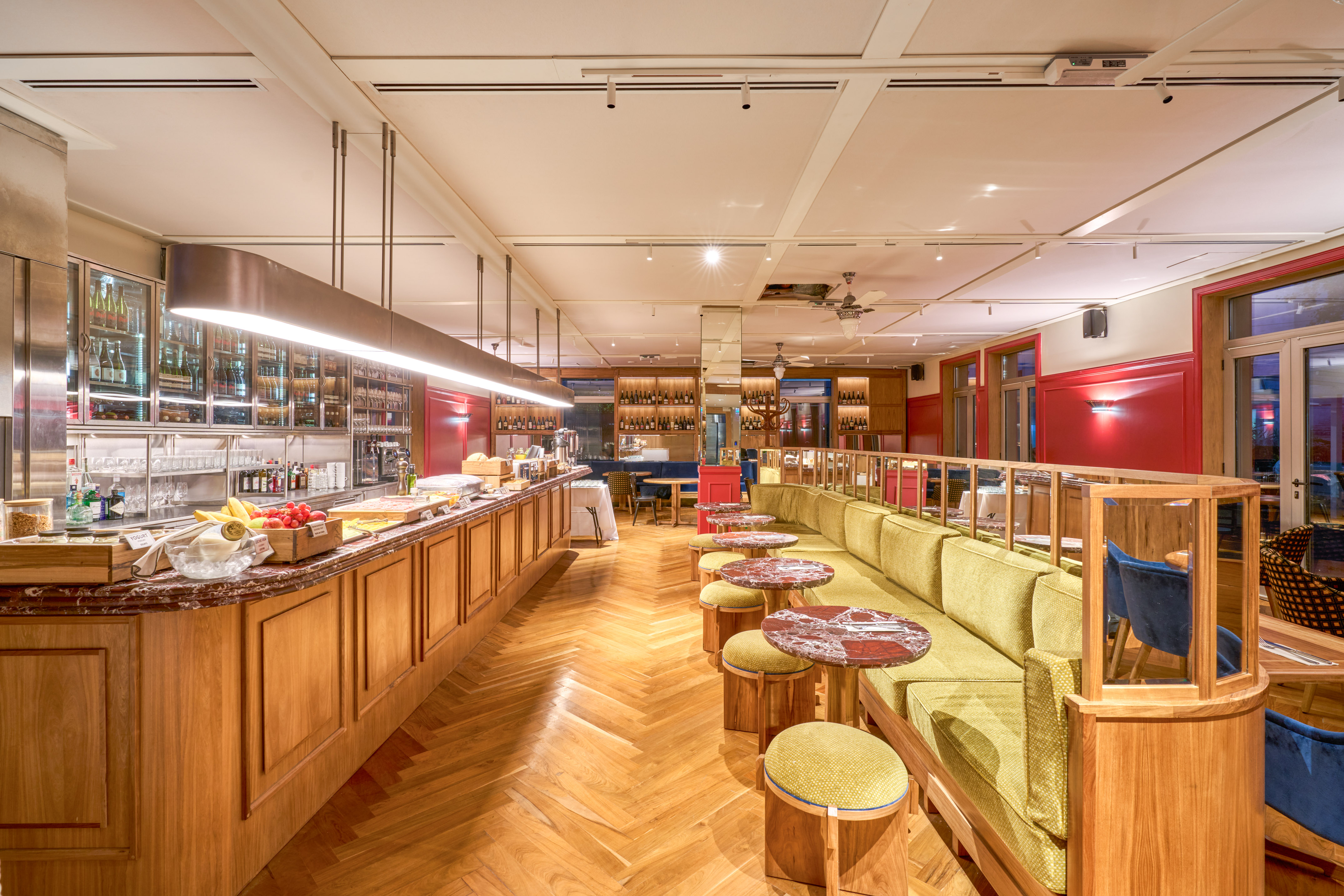 Elegant restaurant bar with green banquette, wooden floor, and modern lighting.
