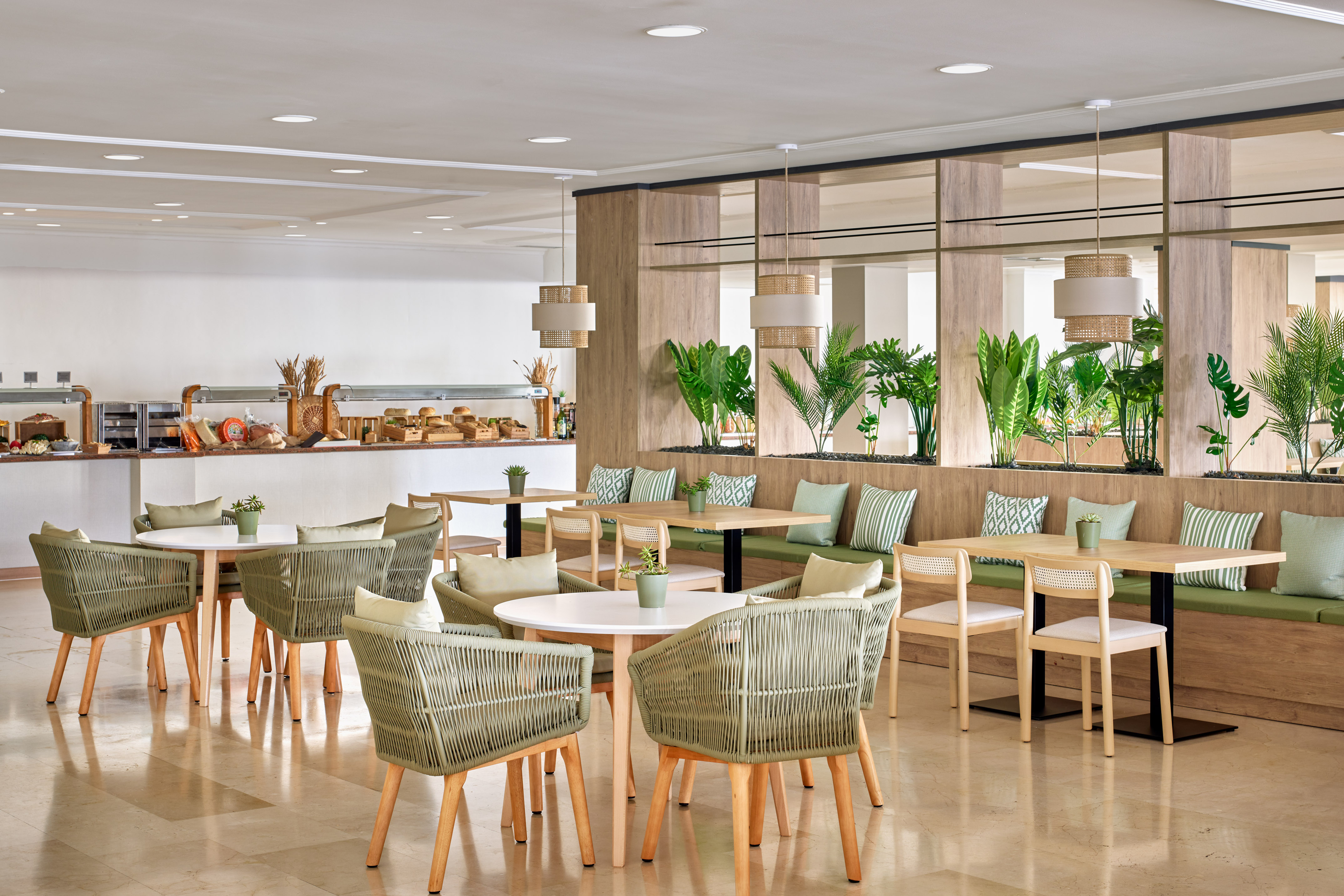 Modern buffet restaurant with green chairs, light wood tables, and tropical plants.