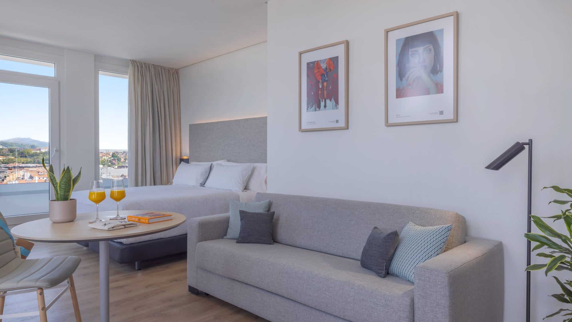 Suite hotelera moderna y luminosa con cama, sofá, y vista panorámica.