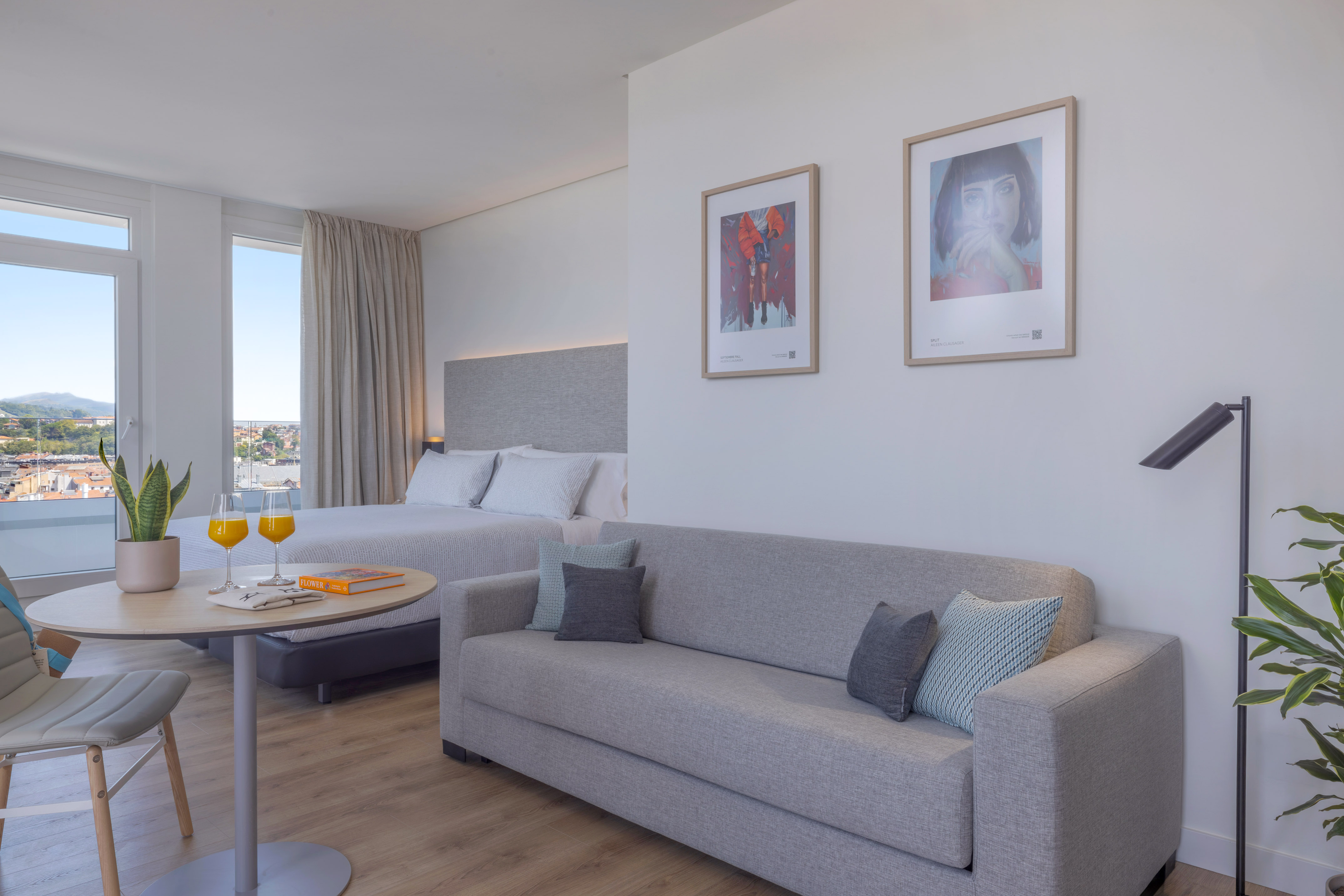 Suite hotelera moderna y luminosa con cama, sofá, y vista panorámica.