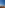 White village with bell tower on red arid land, distant ocean under blue sky.