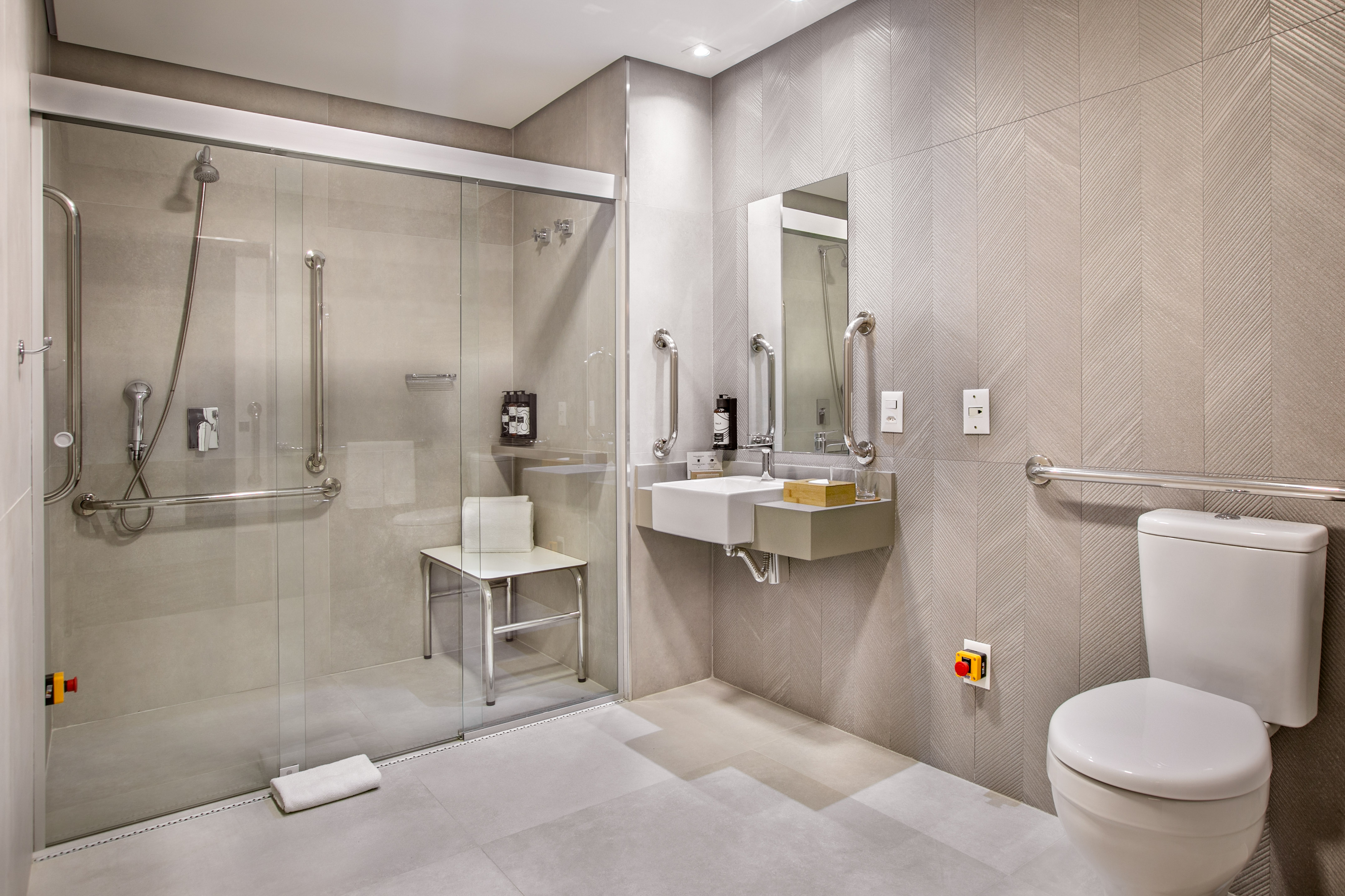 Modern accessible bathroom with roll-in shower, grab bars, and toilet.