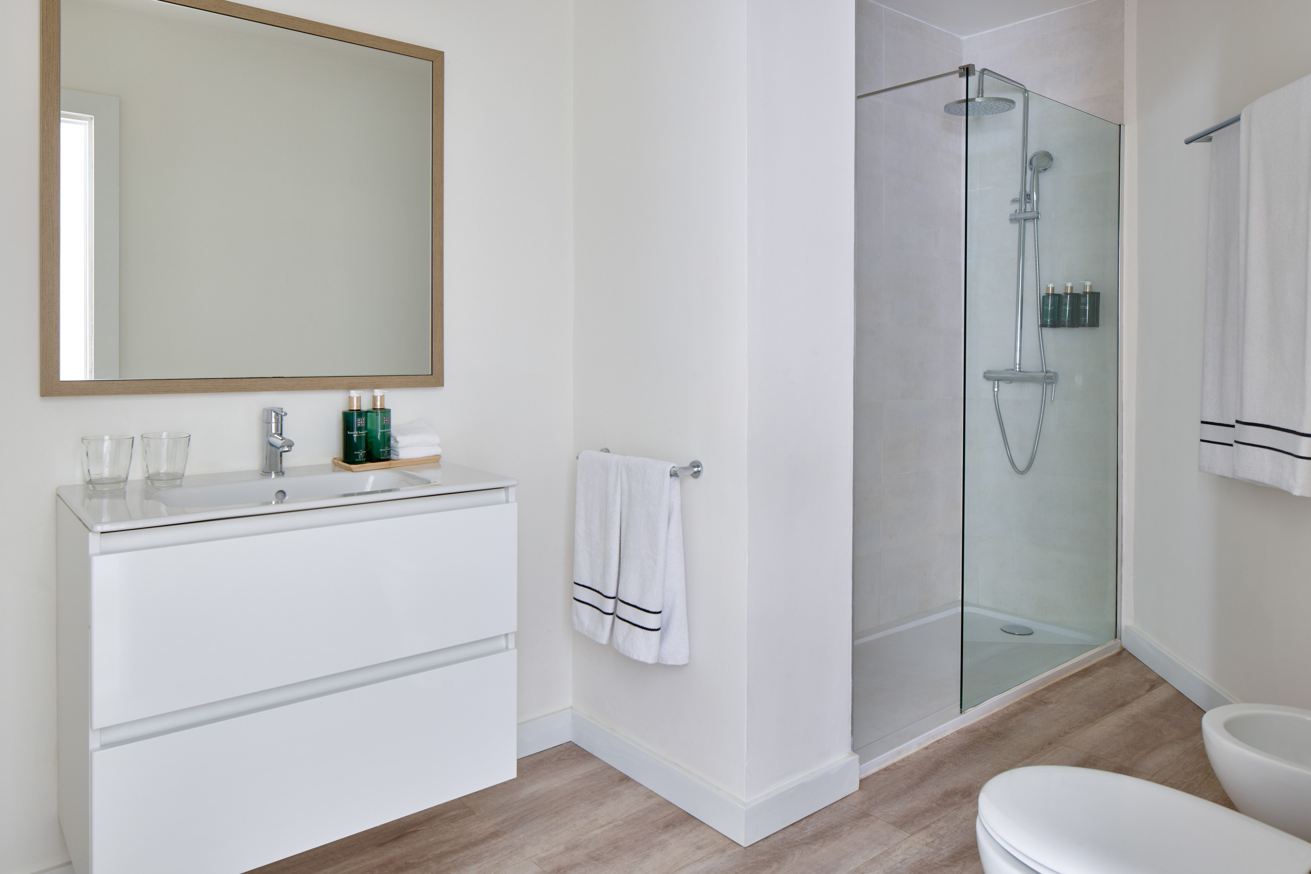 Modern bathroom with white vanity, large mirror, and glass shower.