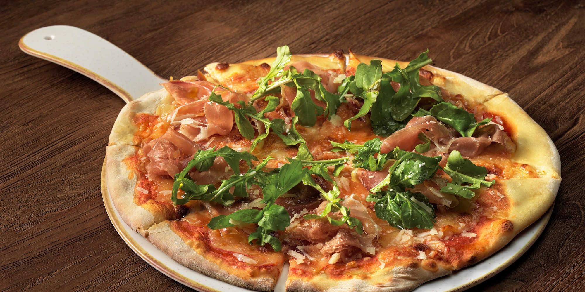 a pizza with greens on a white plate