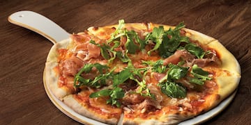 a pizza with greens on a white plate