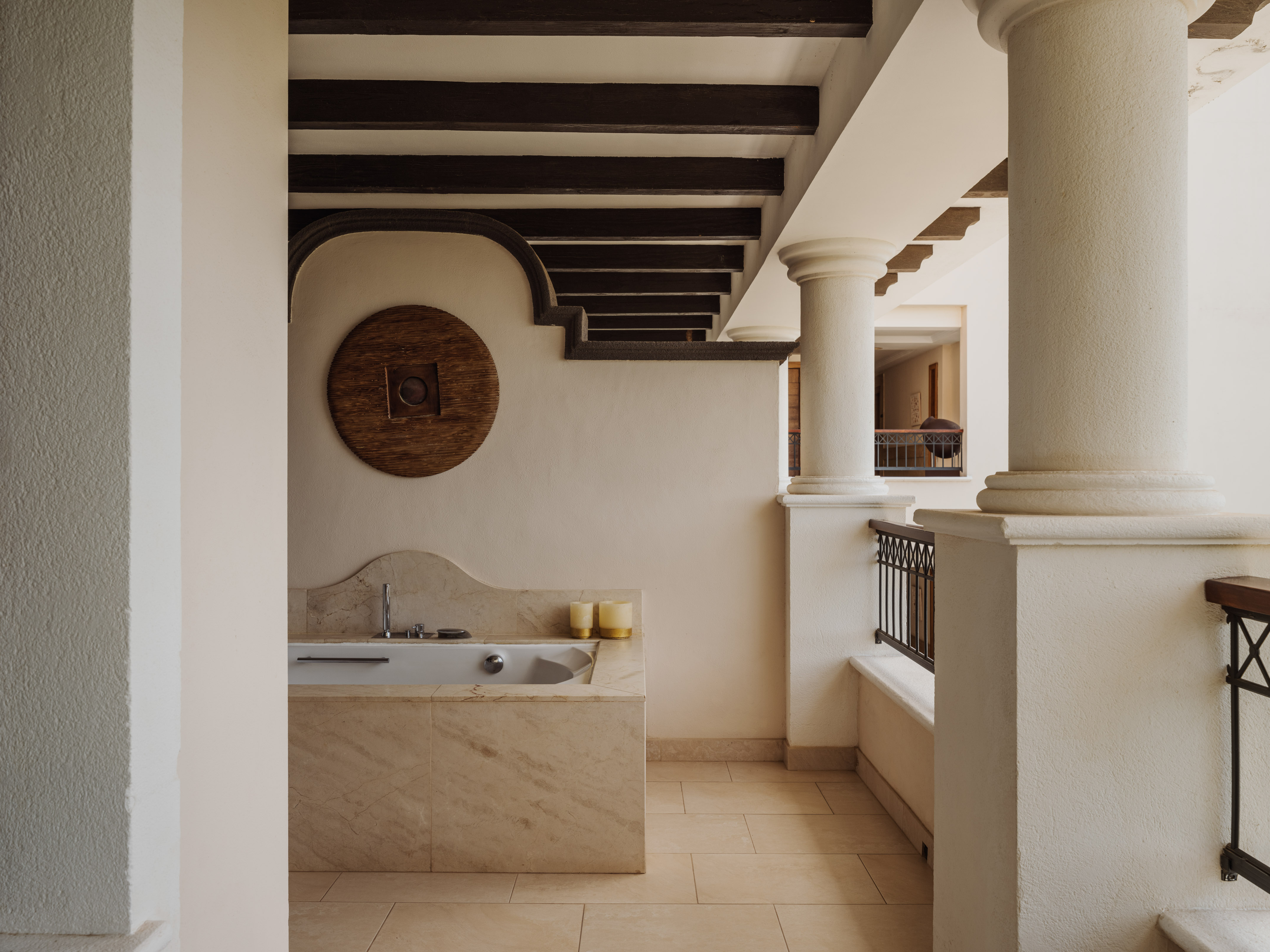 Outdoor marble bathtub on a Mediterranean patio, dark wooden beams.