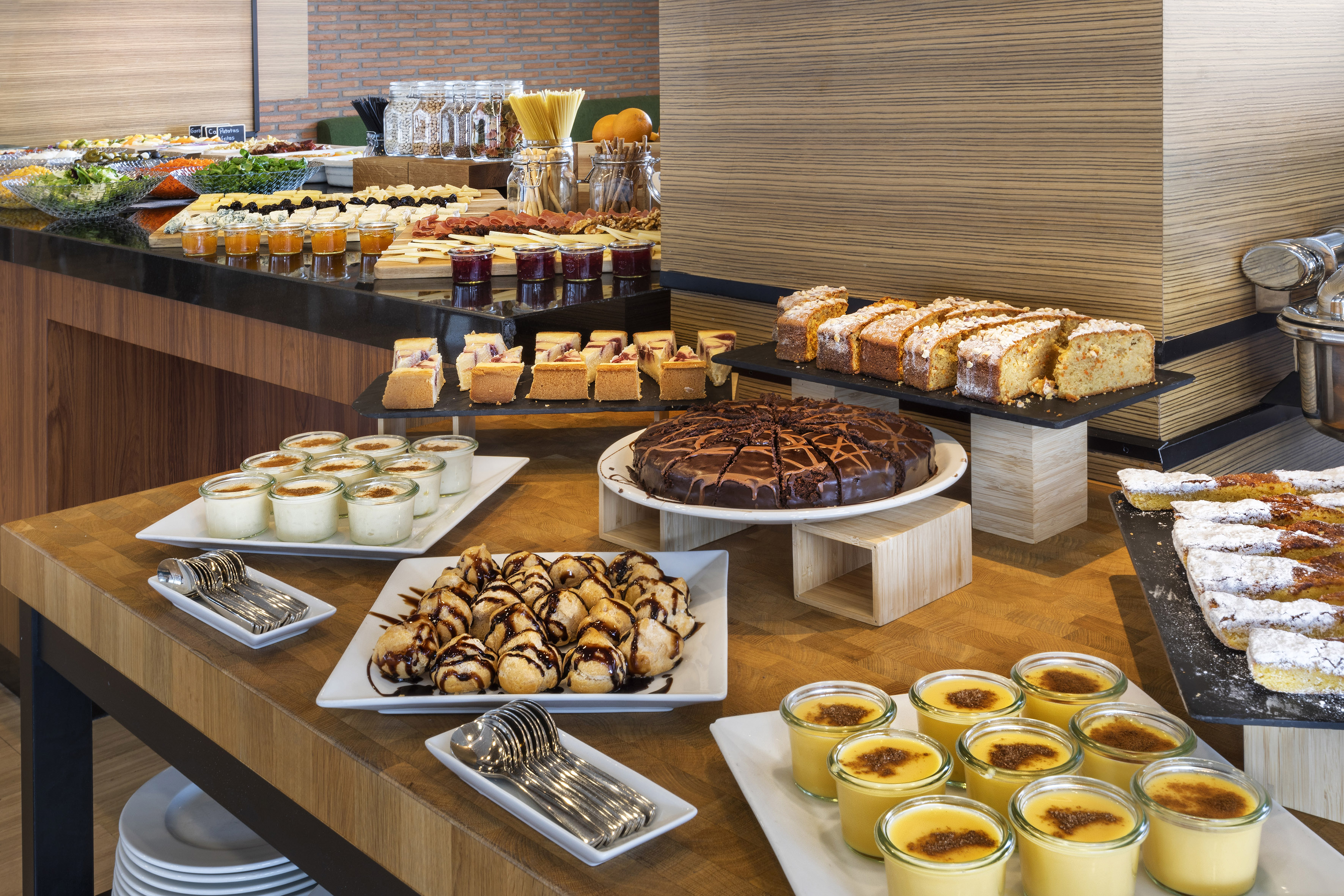 Extensive buffet with desserts, cakes, pastries, salads, and cheeses at a hotel.