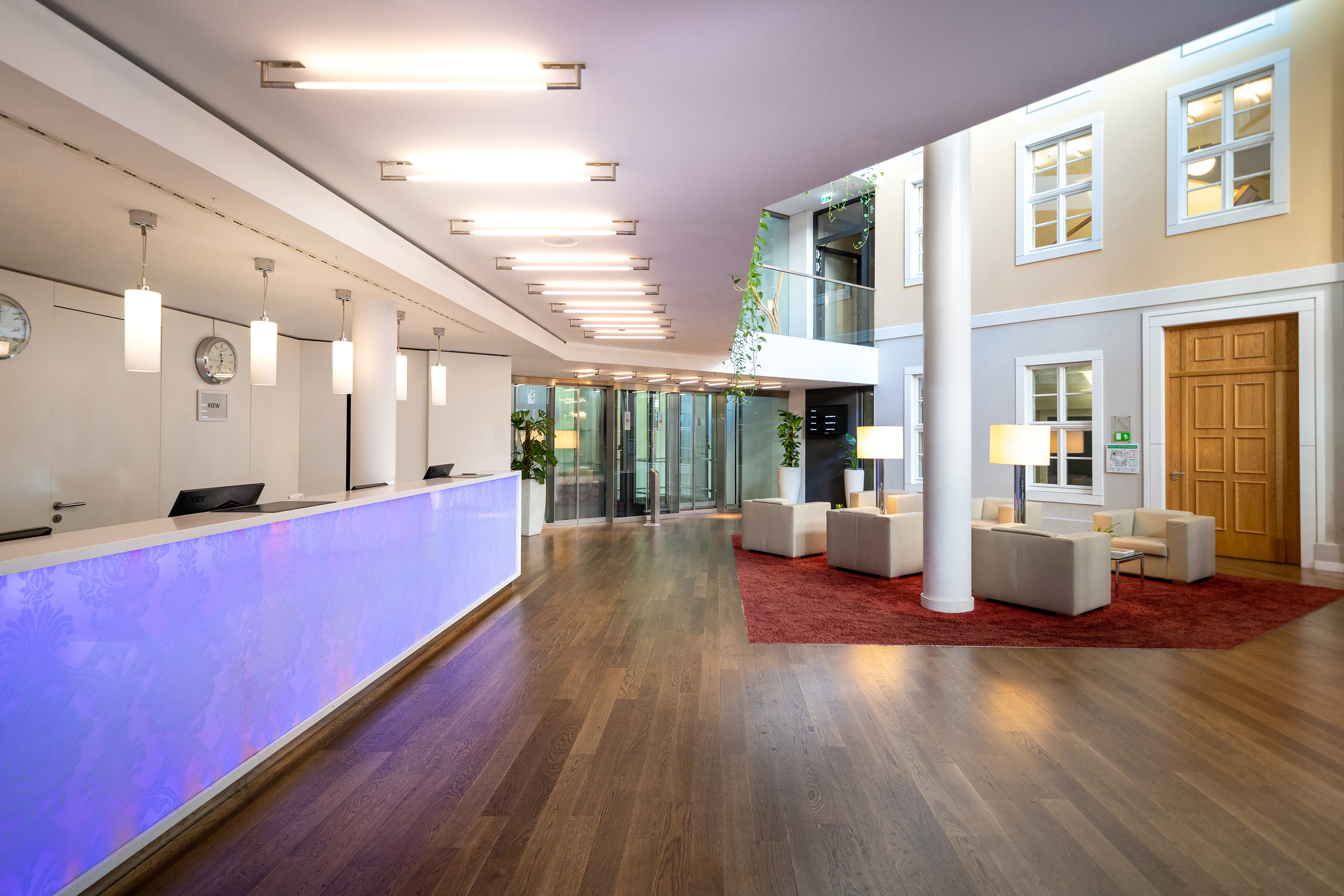 Modern hotel lobby with glowing reception desk, wood floor, and lounge seating. - Innside Dresda, Dresda