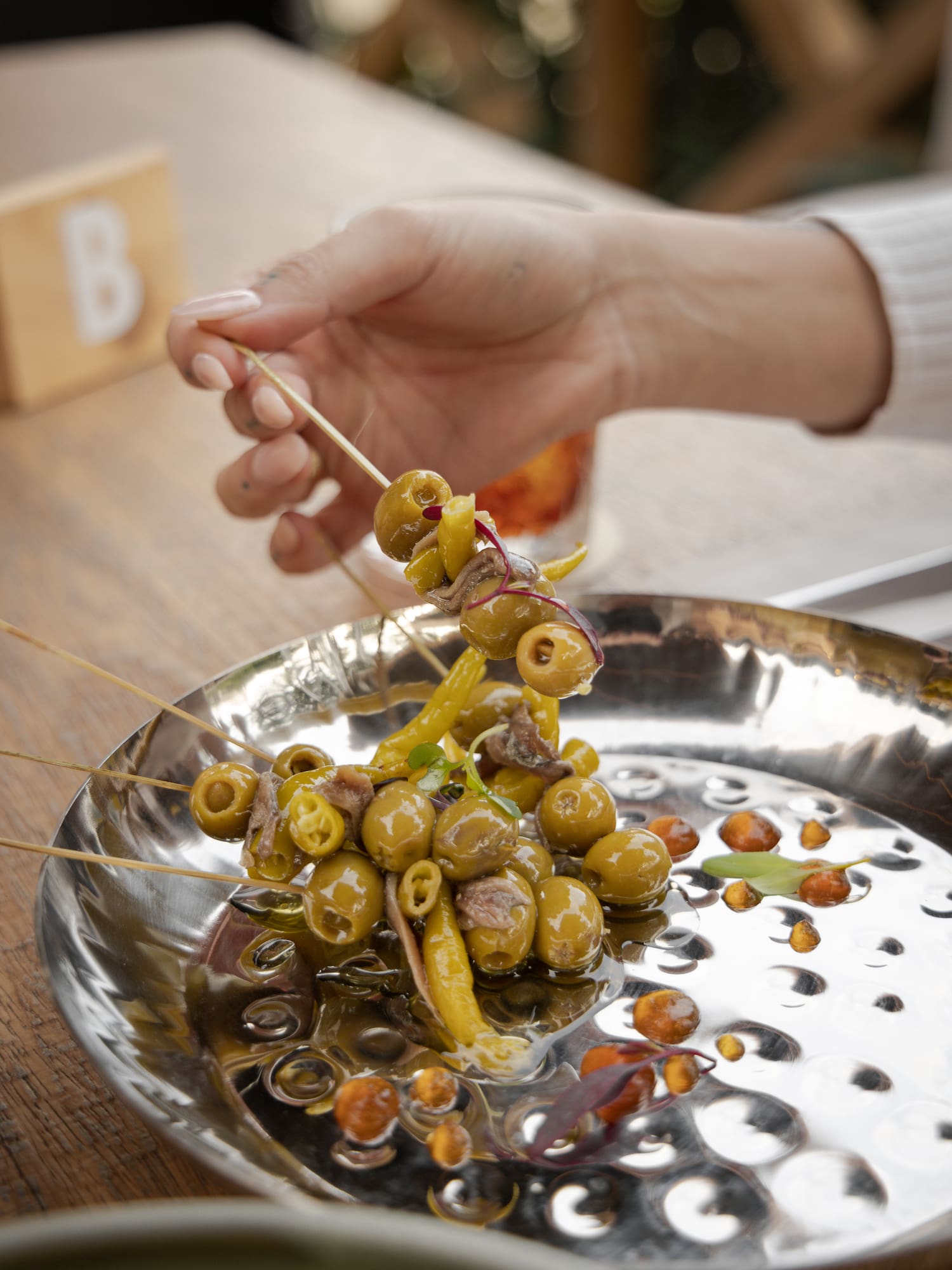 a hand holding a skewer of green olives