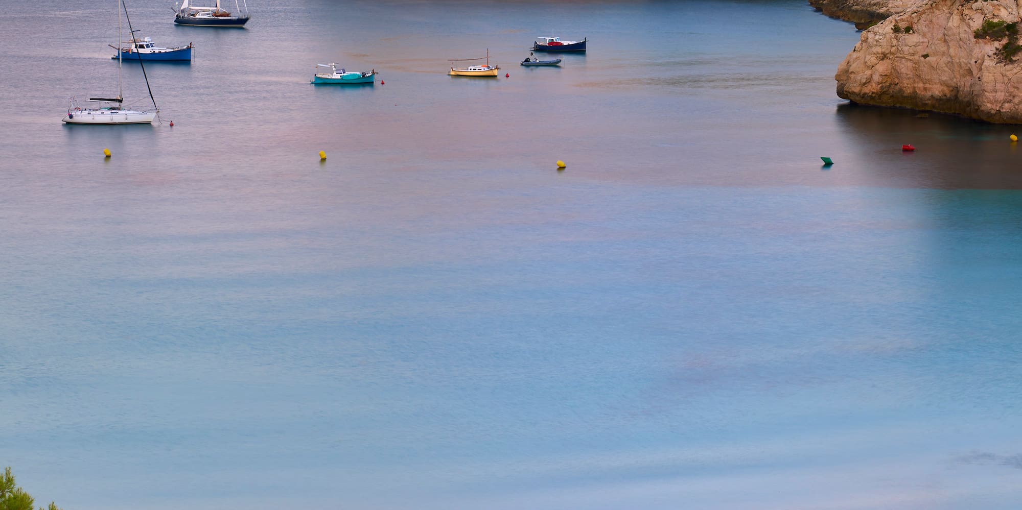 boats in the water with a beach umbrellas and boats