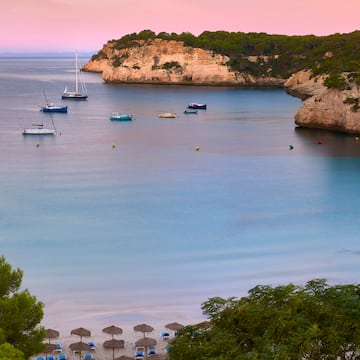 boats in the water with a beach umbrellas and boats