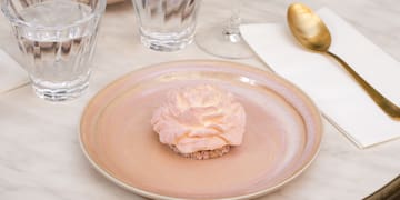 a plate with a pink frosting on it and glasses of water on a table