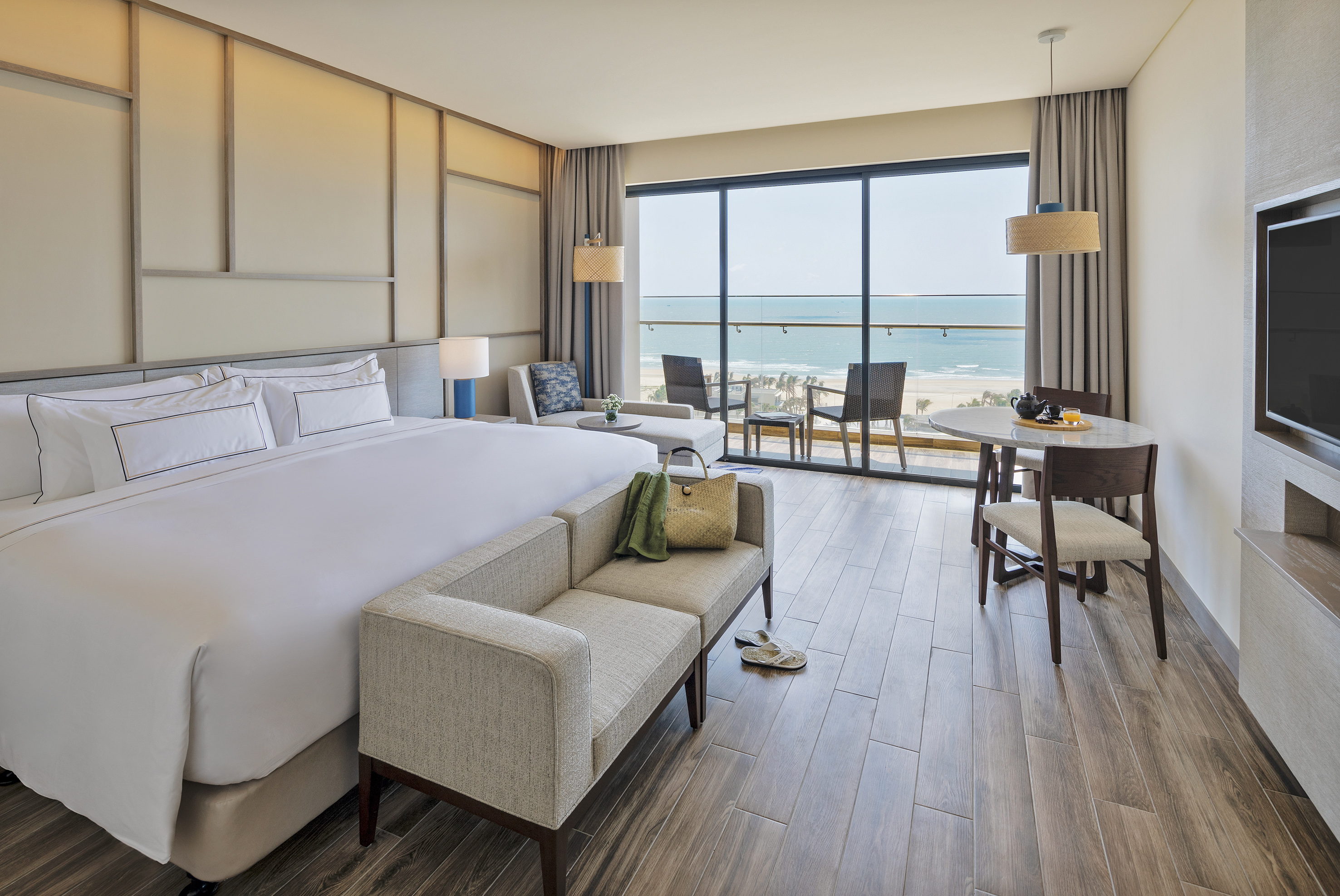 Luxury hotel suite with ocean view balcony, king bed, and modern decor.