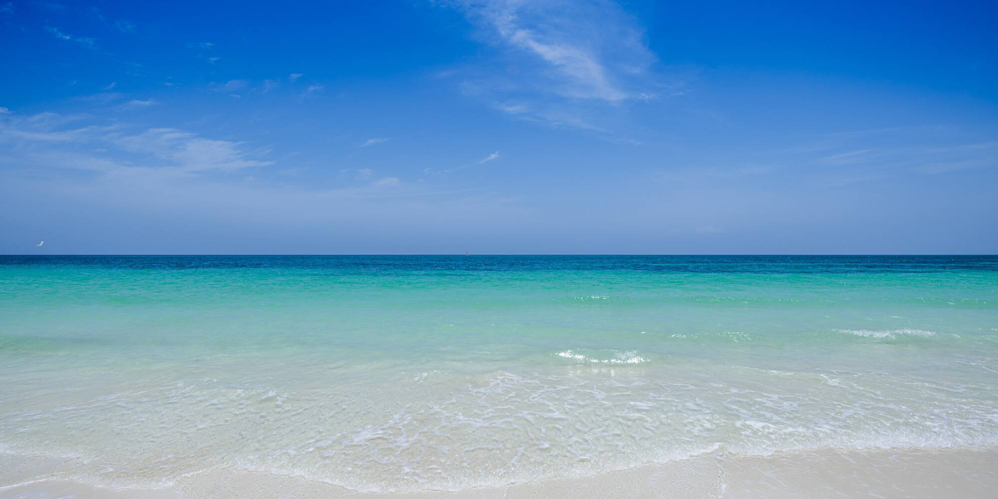 a beach with clear water and blue sky