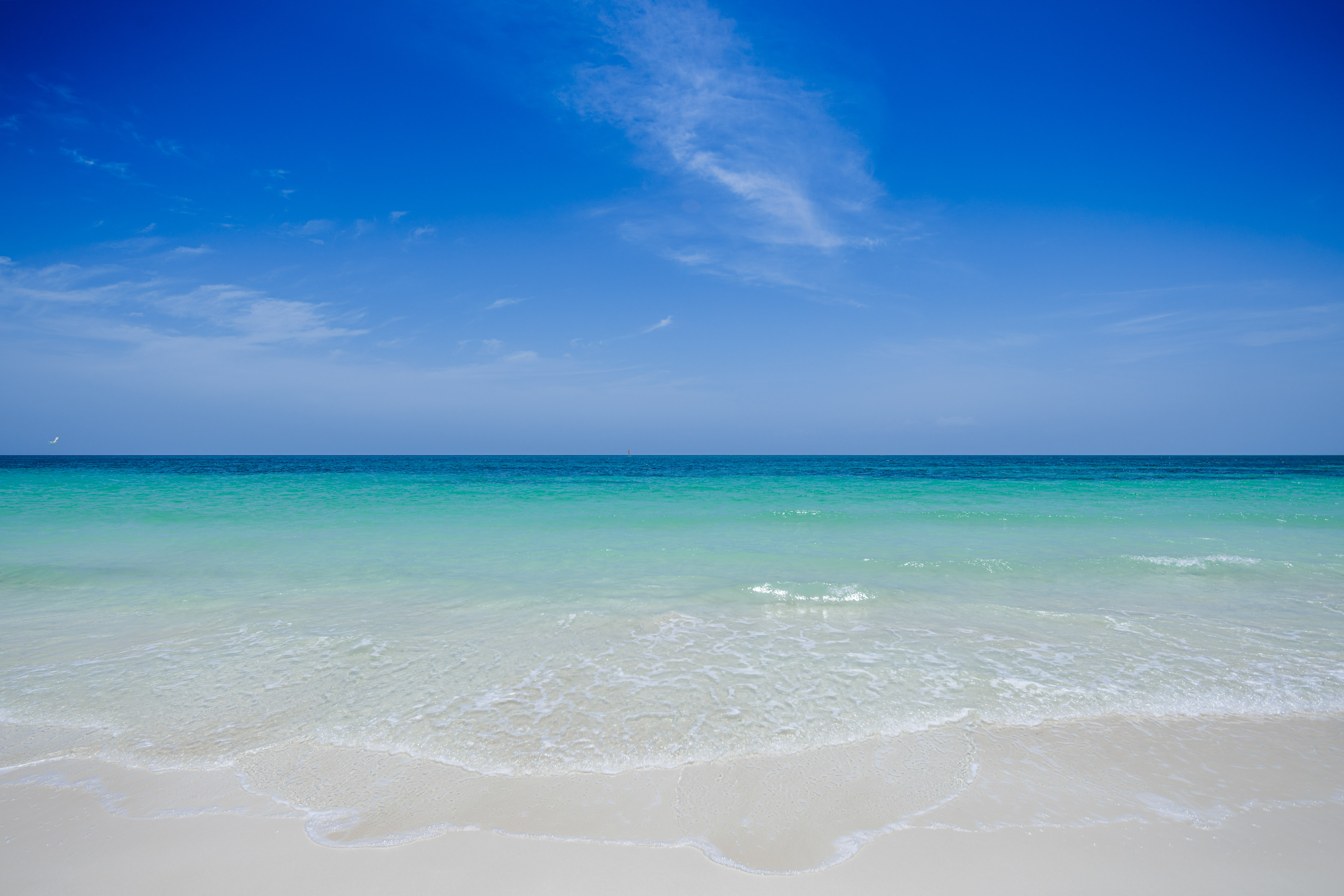 a beach with clear water and blue sky