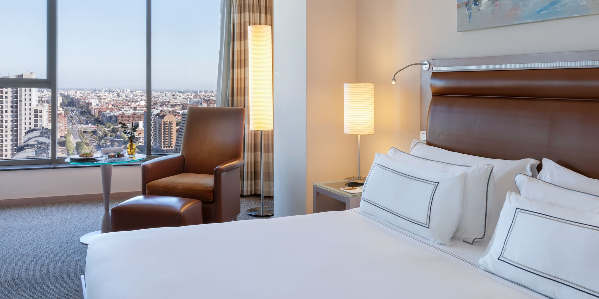 a hotel room with a large window and a large city view