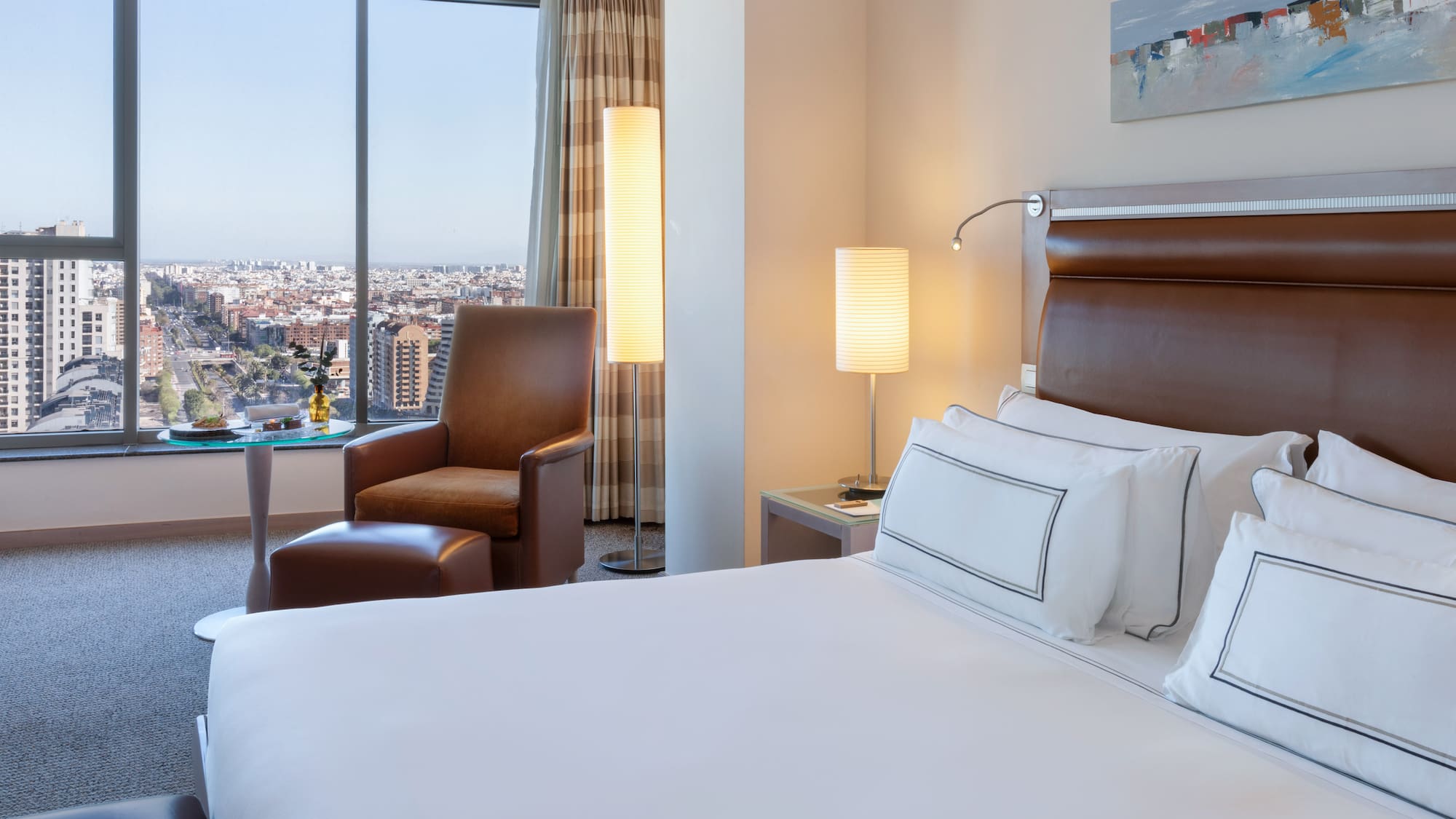 a hotel room with a large window and a large city view
