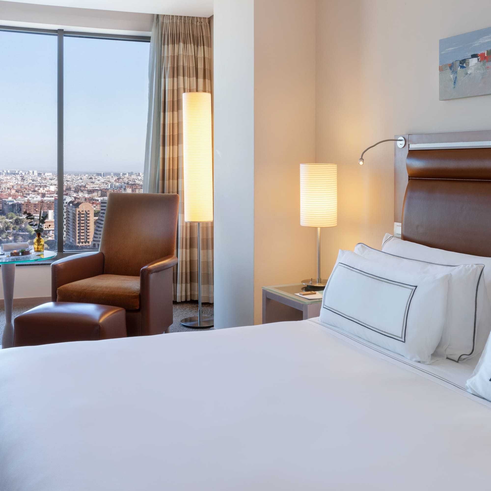 a hotel room with a large window and a large city view