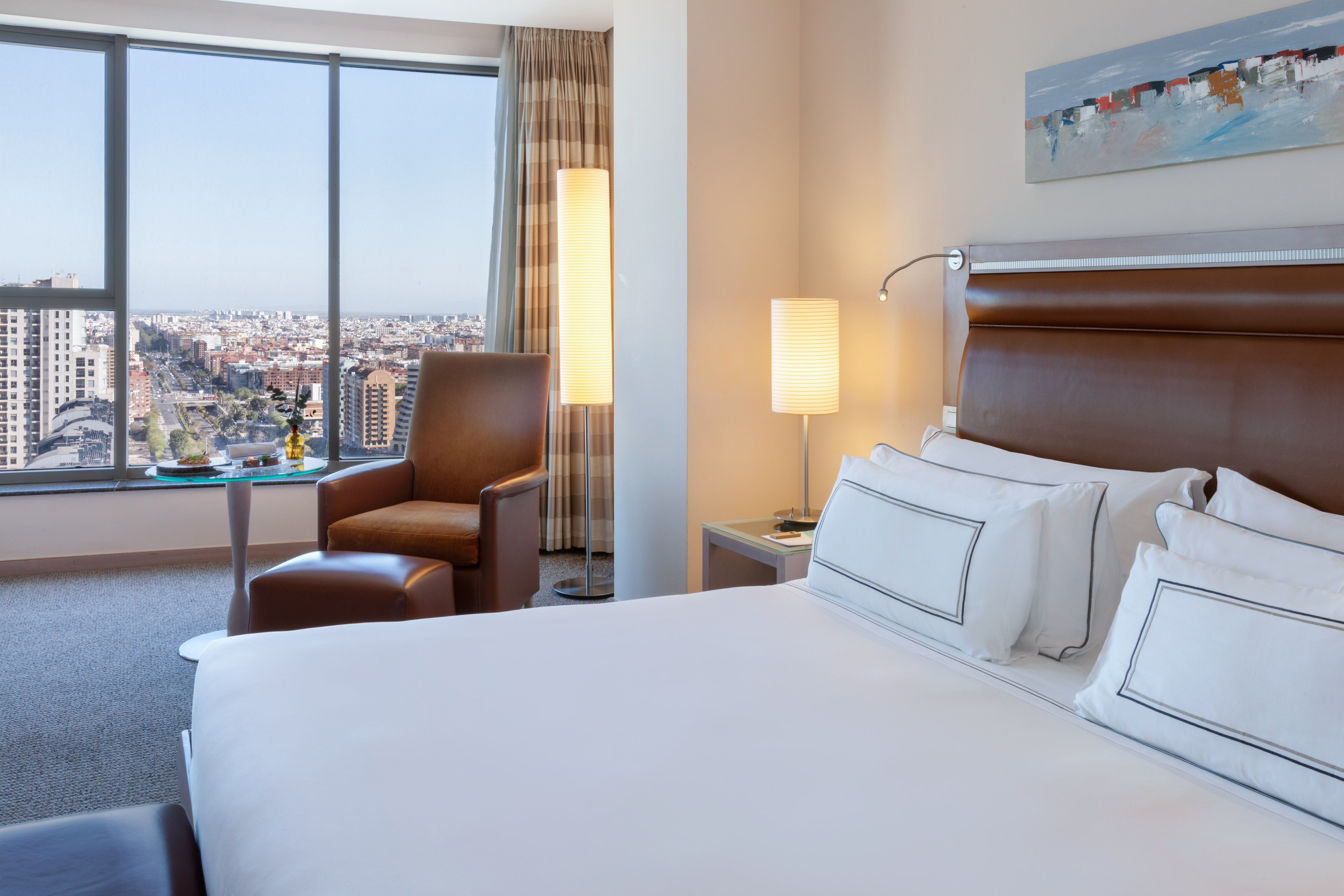a hotel room with a large window and a large city view