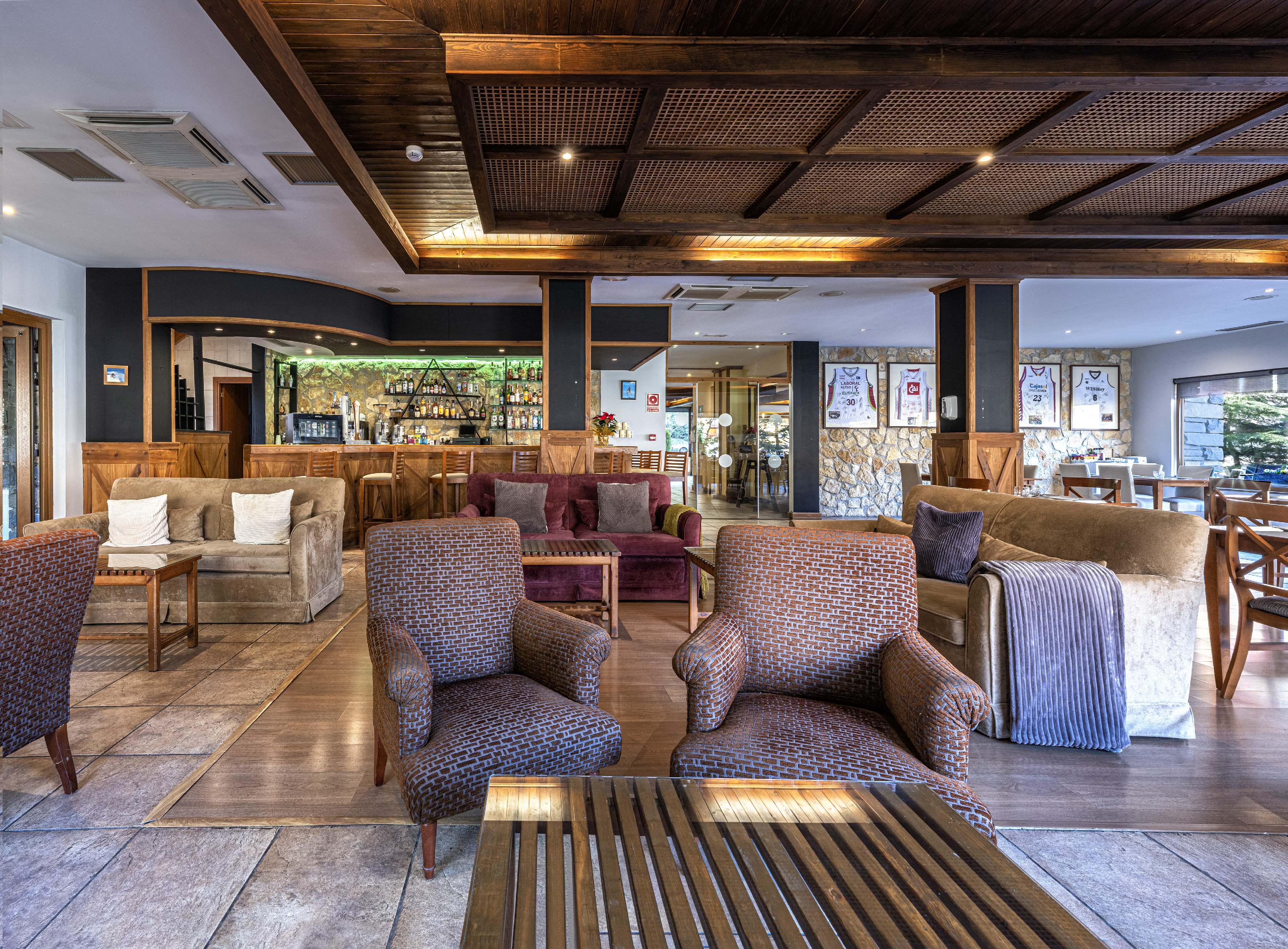 Warm hotel lounge bar with cozy seating, wooden beams, and illuminated bar.